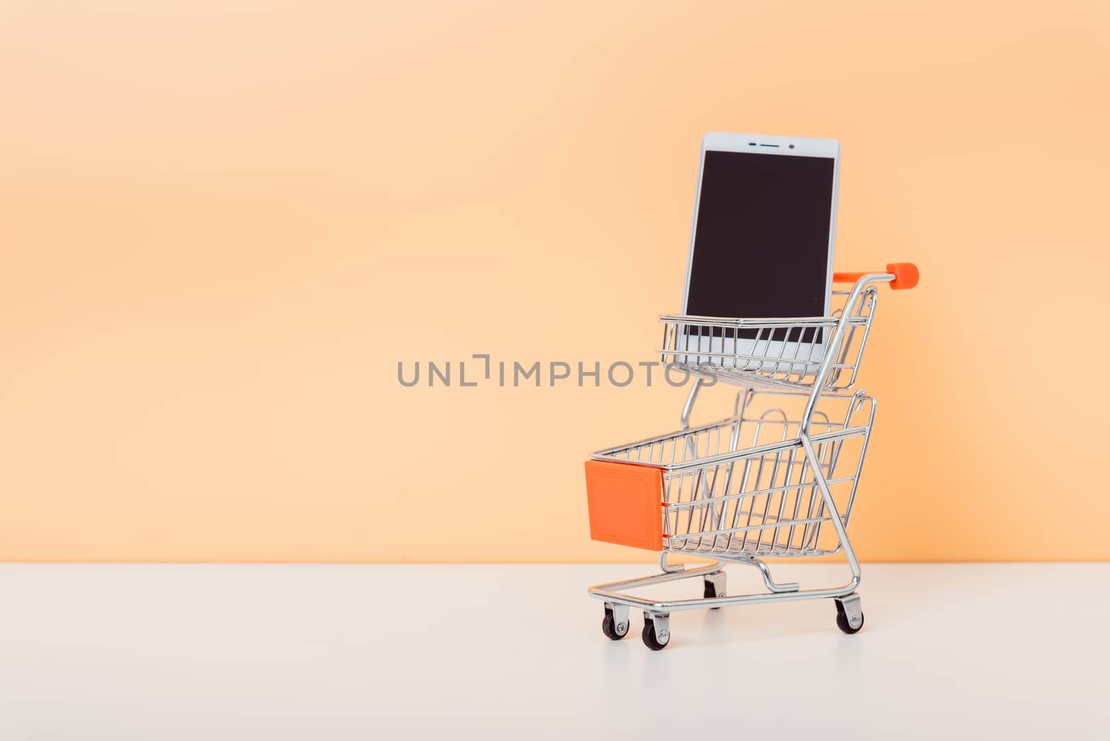 Mock up shoppong online cart and smartphone on desk table office soft yellow wall