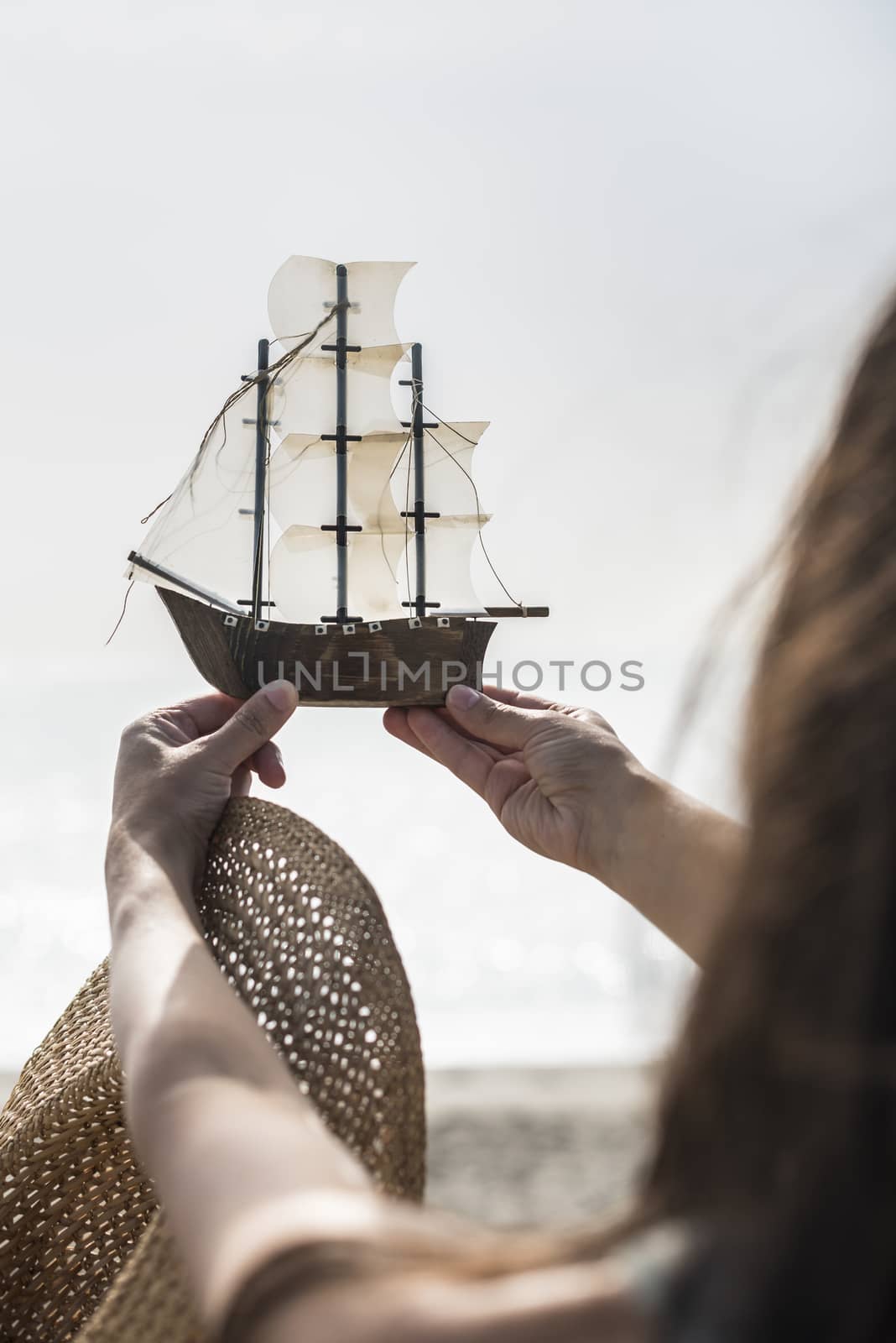 Woman with hat hold boat model on the beach