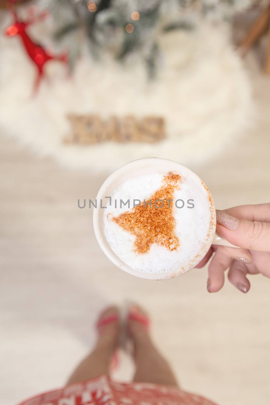 Female holding cappuccino with Christmas tree design on froth by lovleah