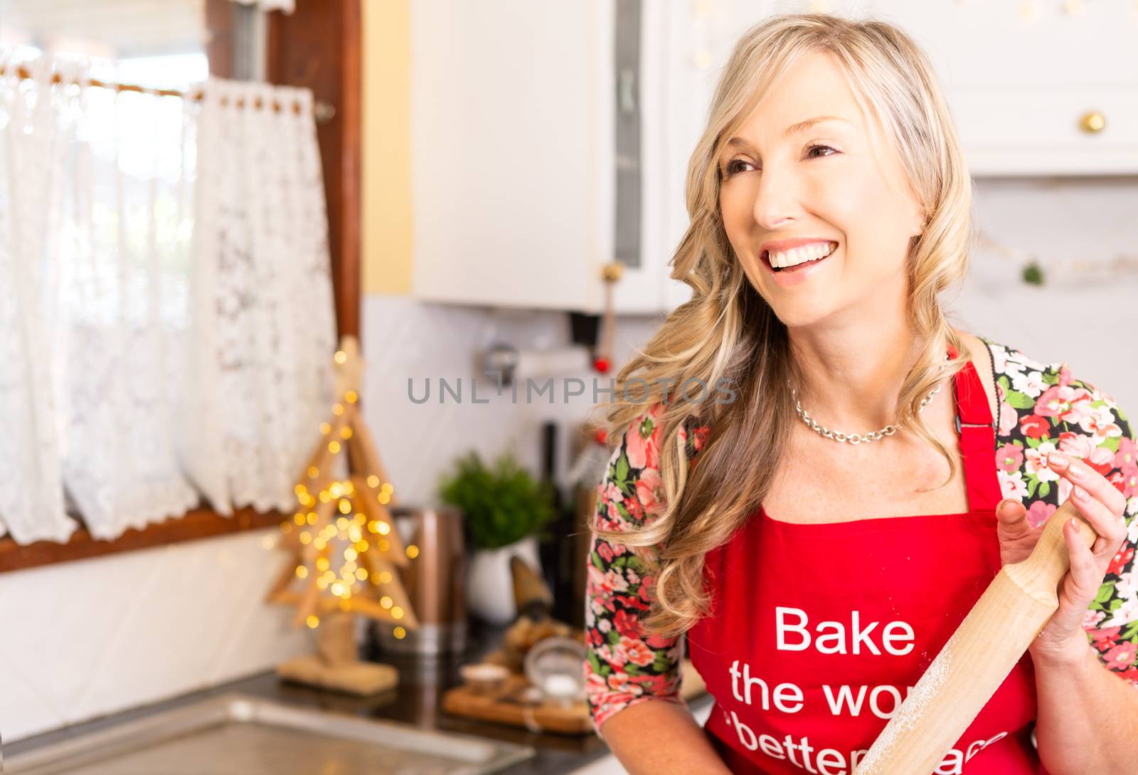 Woman in the kitchen with baking ingredients, and holding a rolling pin at Christmas time