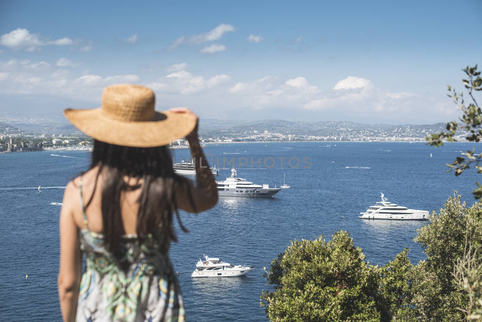 Woman with summer hat watching yachts. French riviera