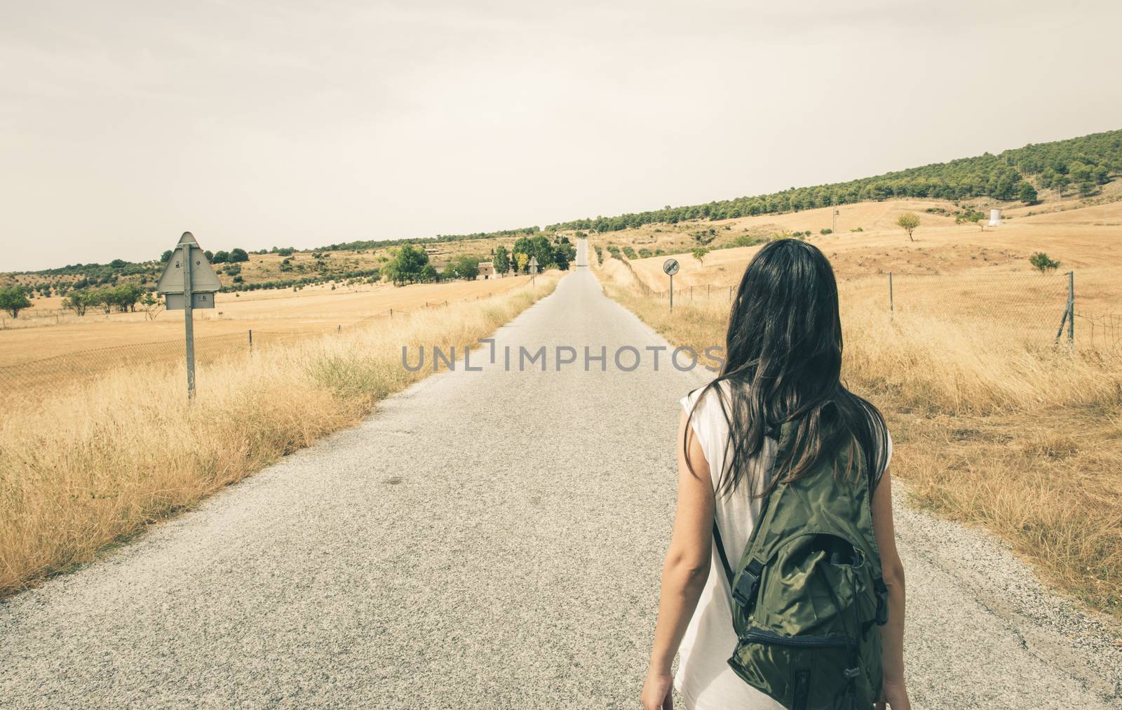 Woman with backpack walking on the road
