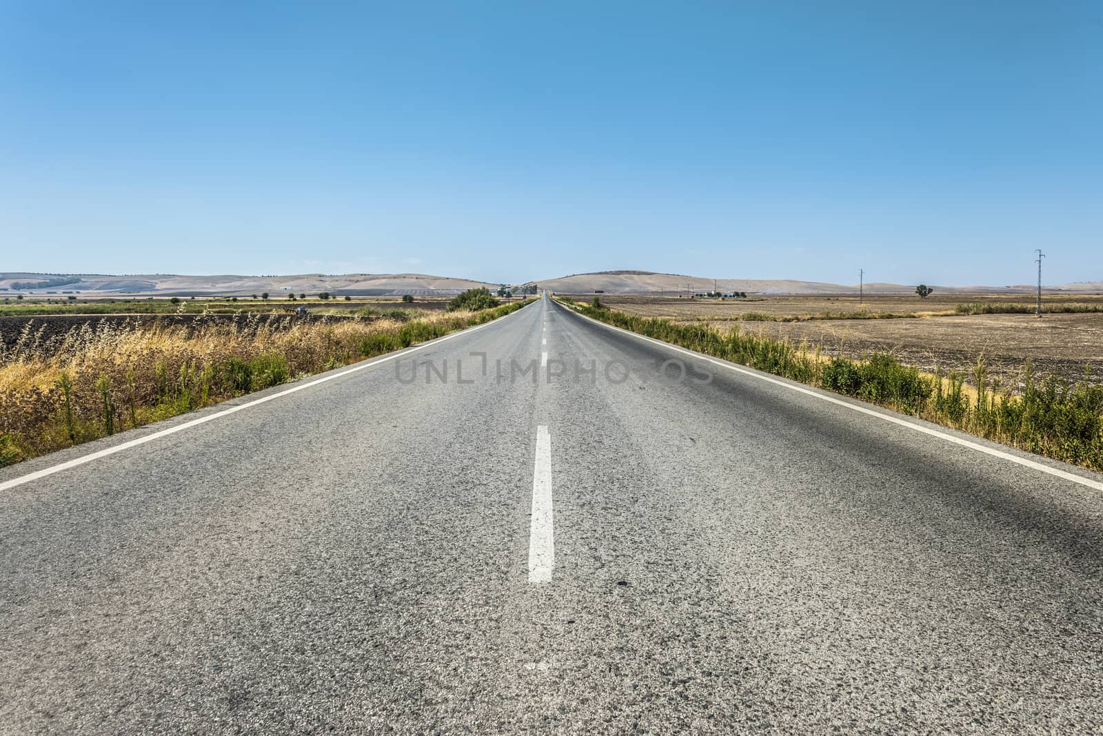 Long asphalt road and blue sky.