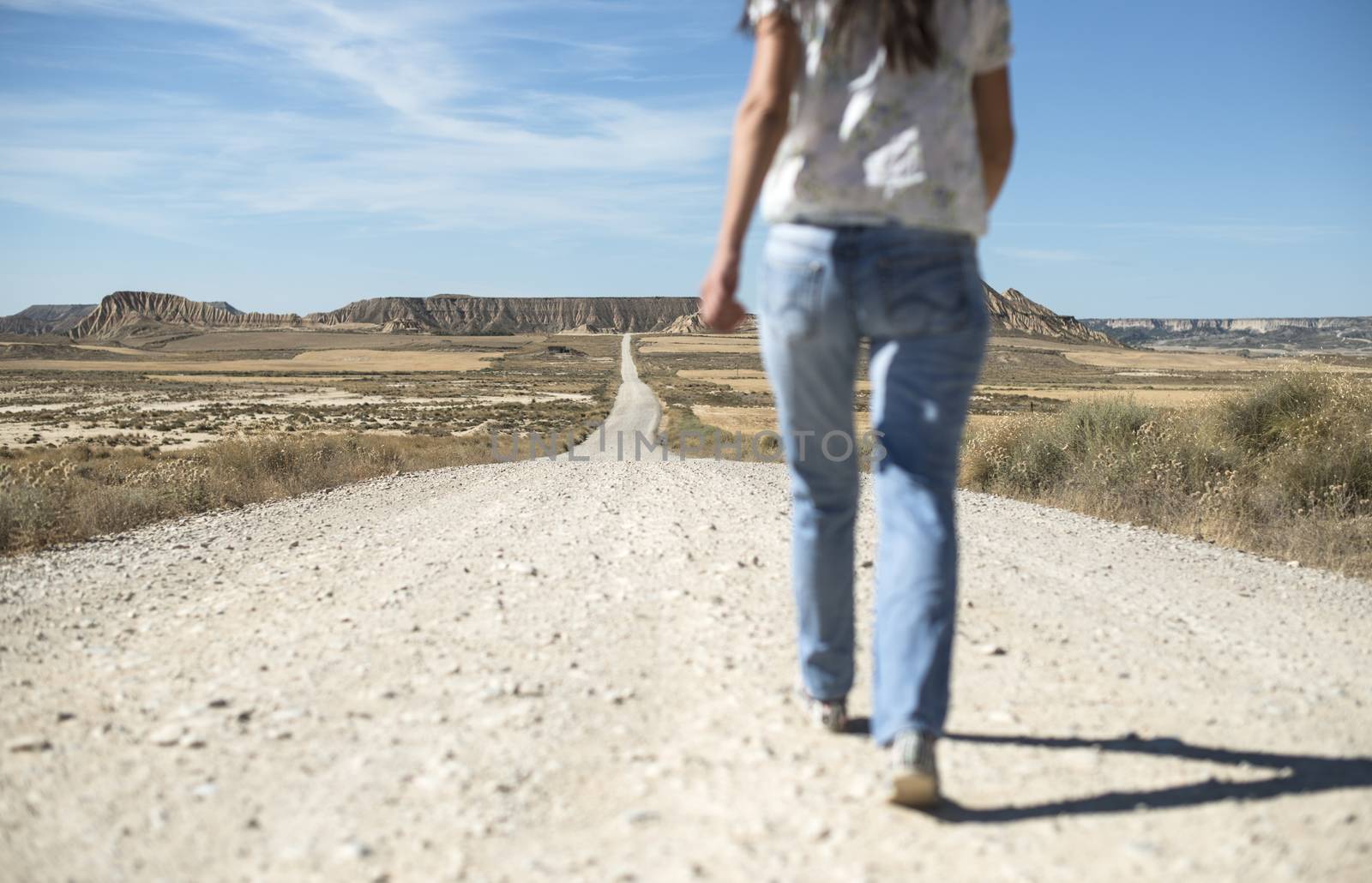 Woman with jeans walking on wild west dirt road