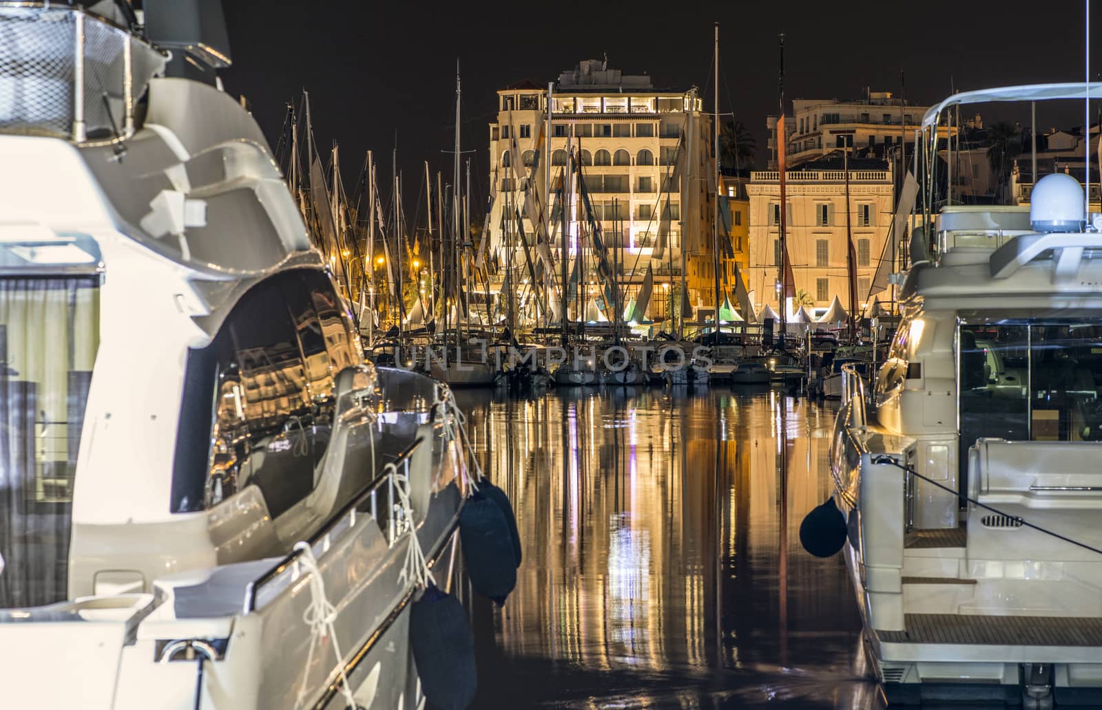 Yachts in the cannes bay at night.  Illuminated buildings 