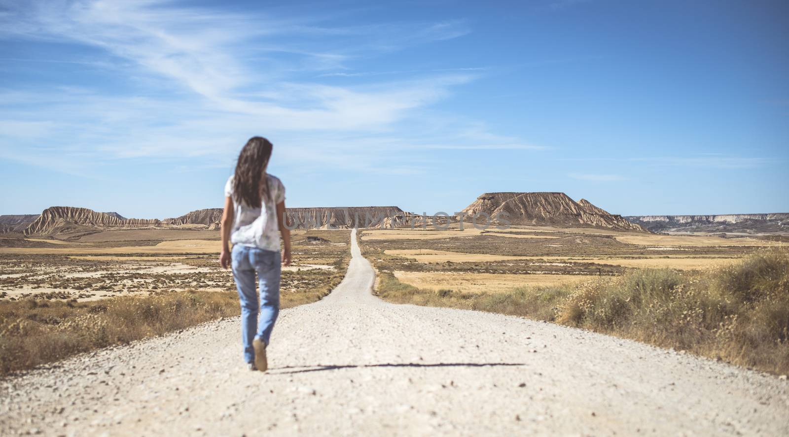 Woman walking on dirt road. Looking like a movie