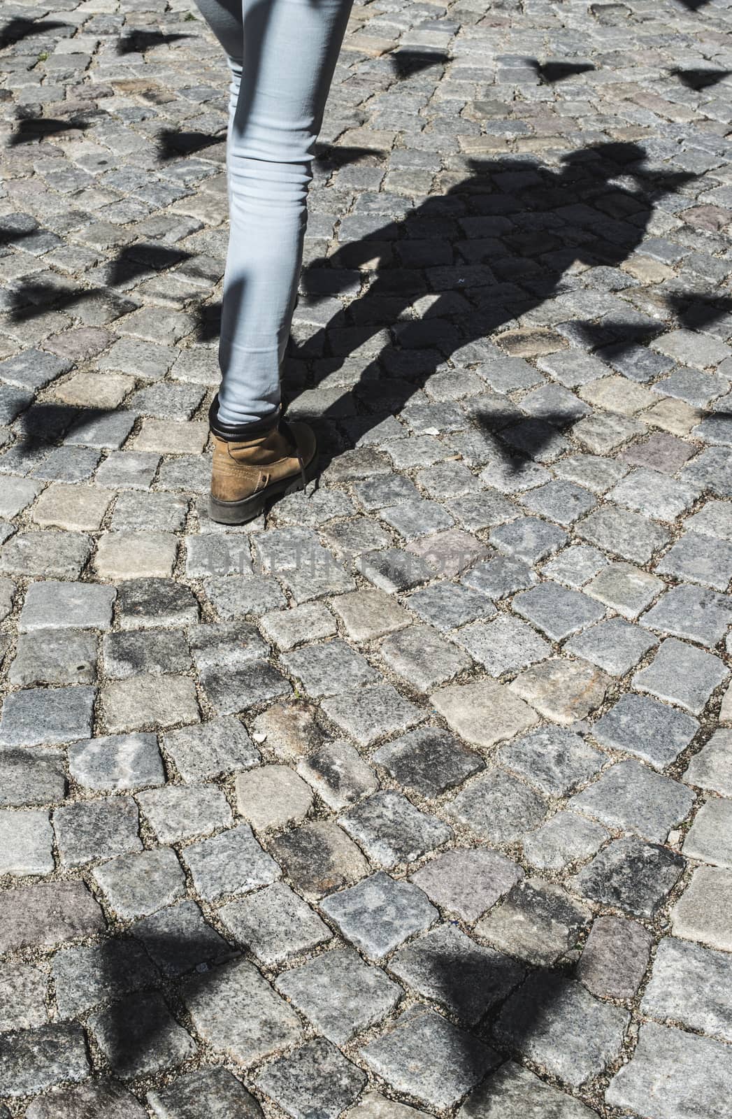 Shadows of festival flags. People wlak on paved road