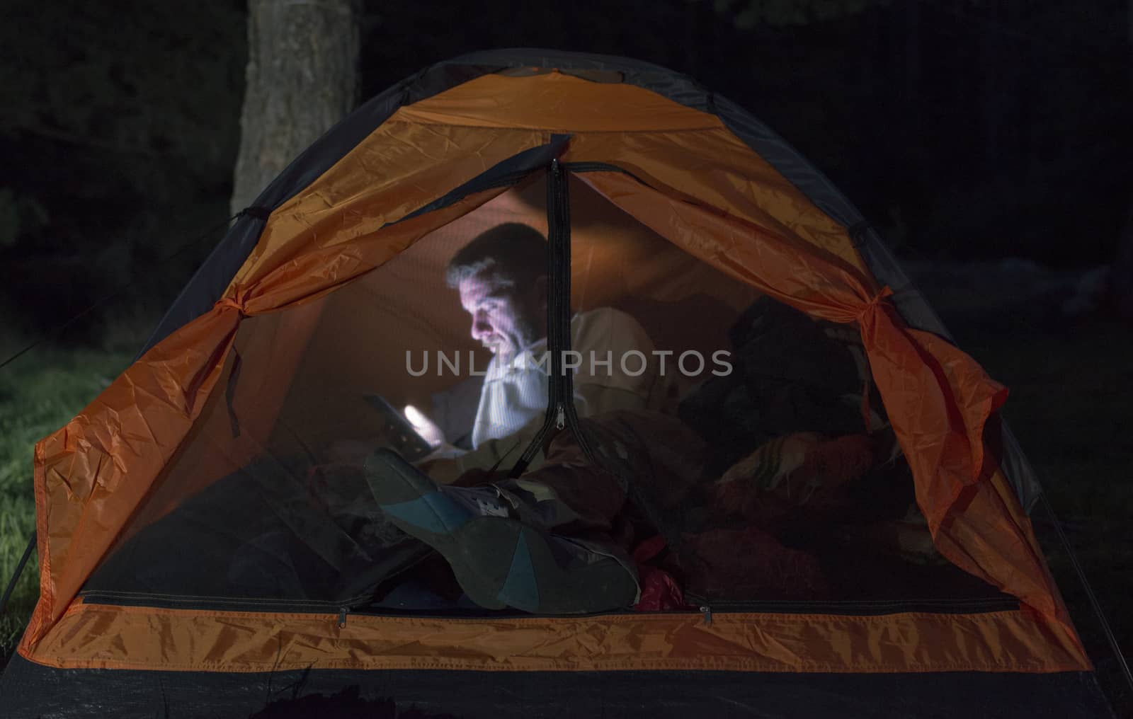 Man watching his smartphone in a tent. by deyan_georgiev