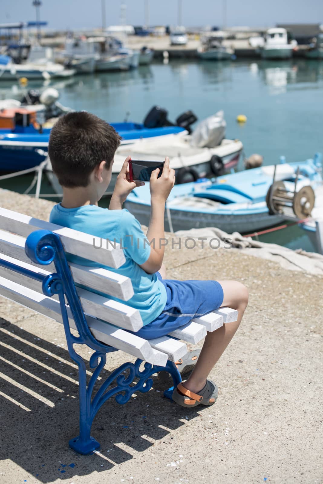 Child sitting on a bench on the beach  by deyan_georgiev