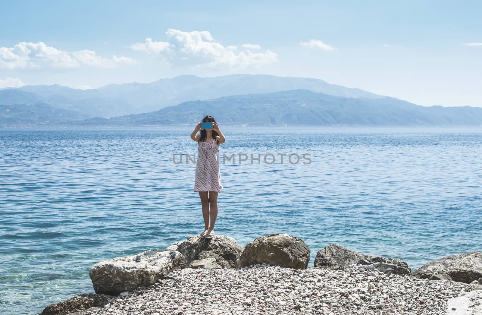 Woman taking pictures with smartphone on the beach. 