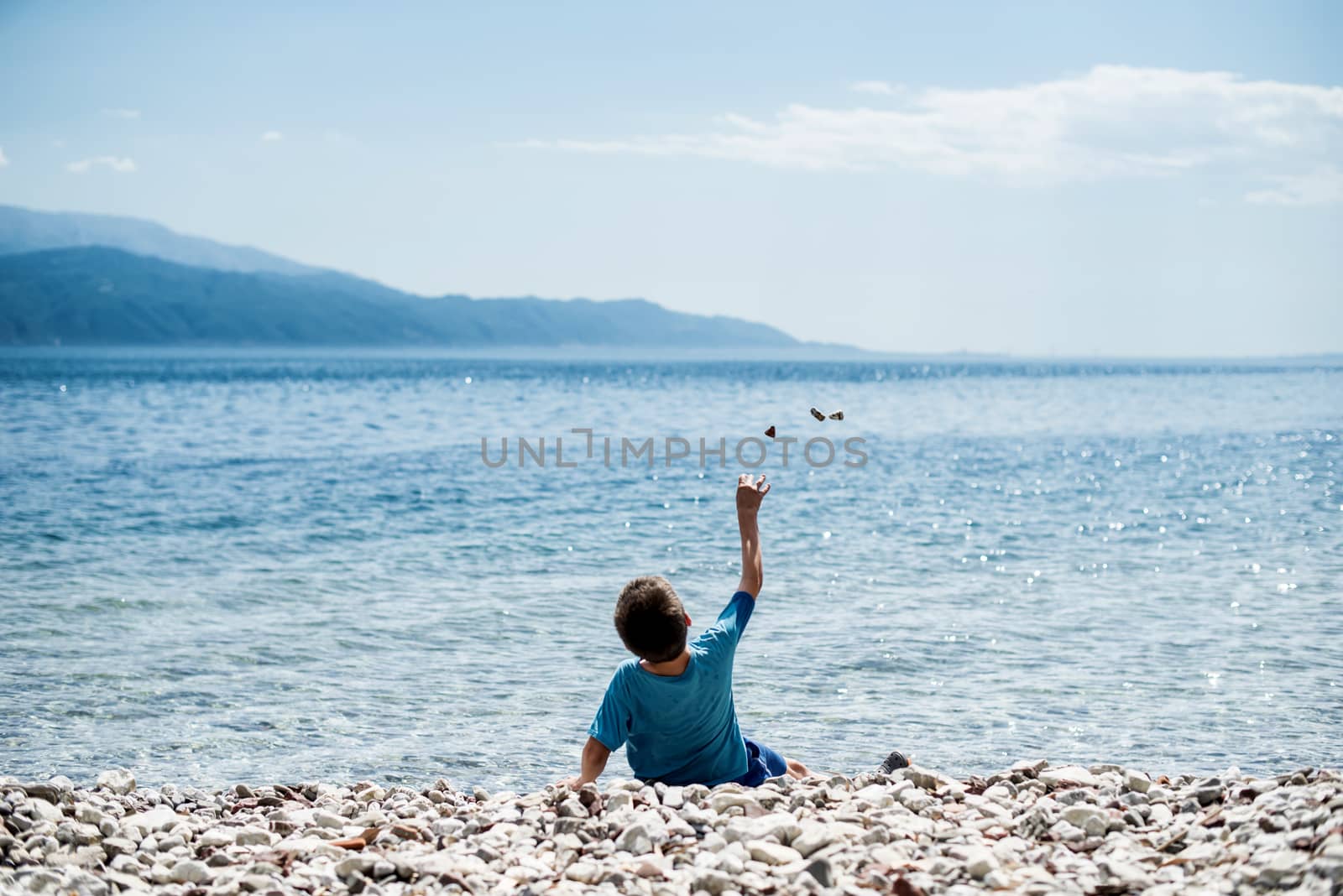 Children throw stones at the water of the sea by deyan_georgiev