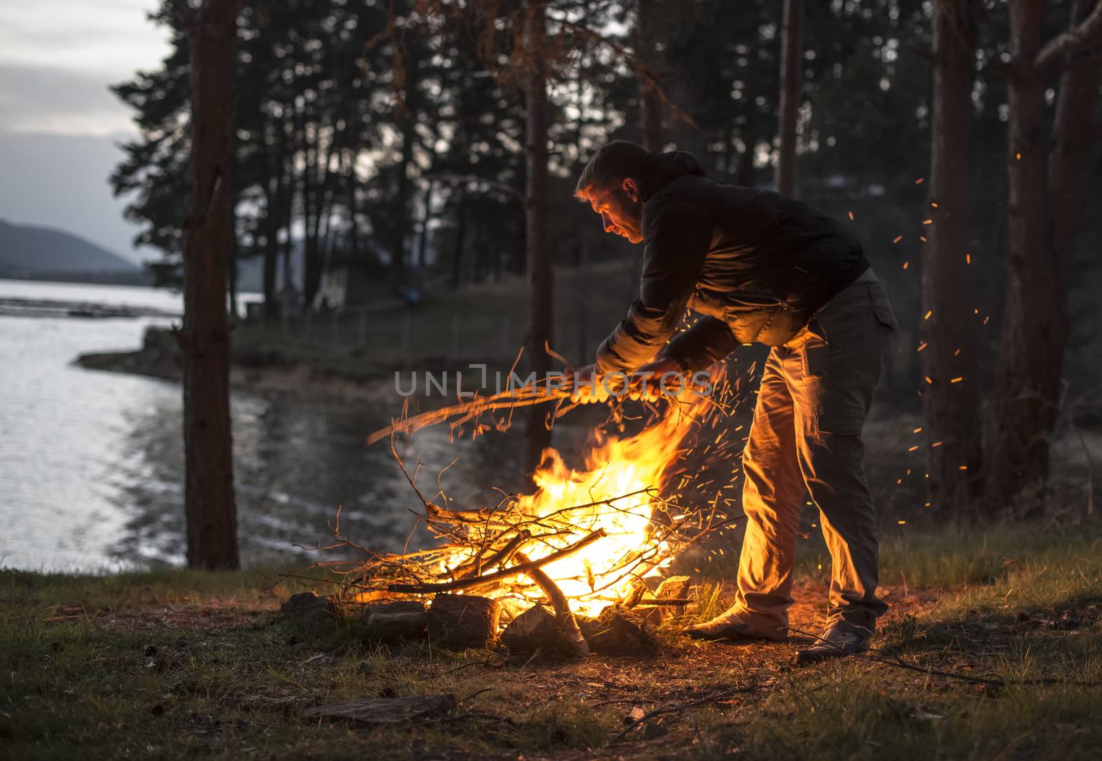 Man lights a fire in the fireplace in nature by deyan_georgiev