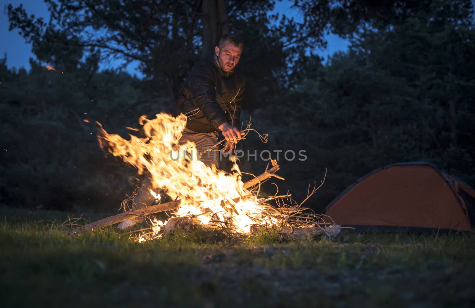 Man lights a fire in the fireplace in nature by deyan_georgiev