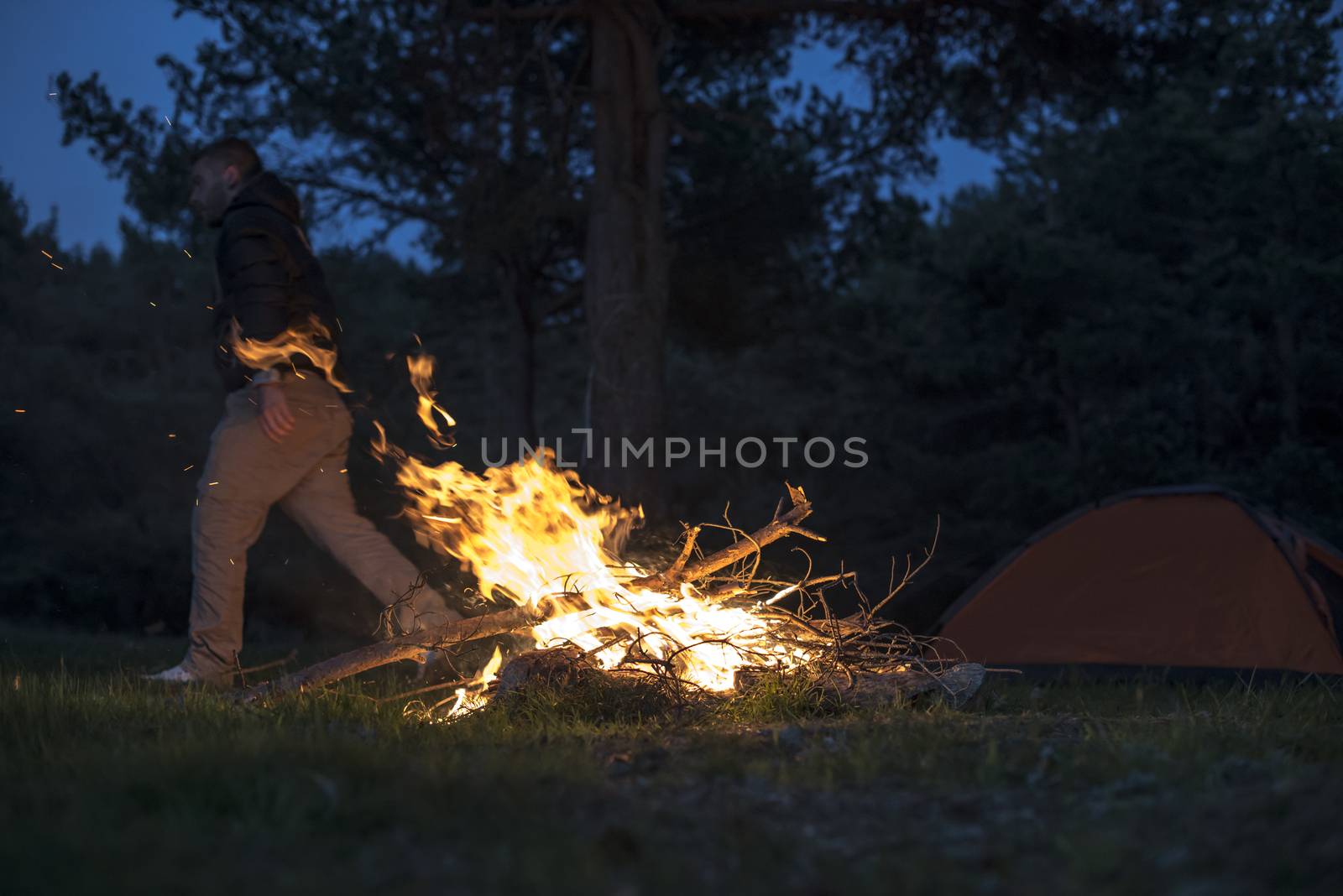 Man lights a fire in the fireplace in nature by deyan_georgiev