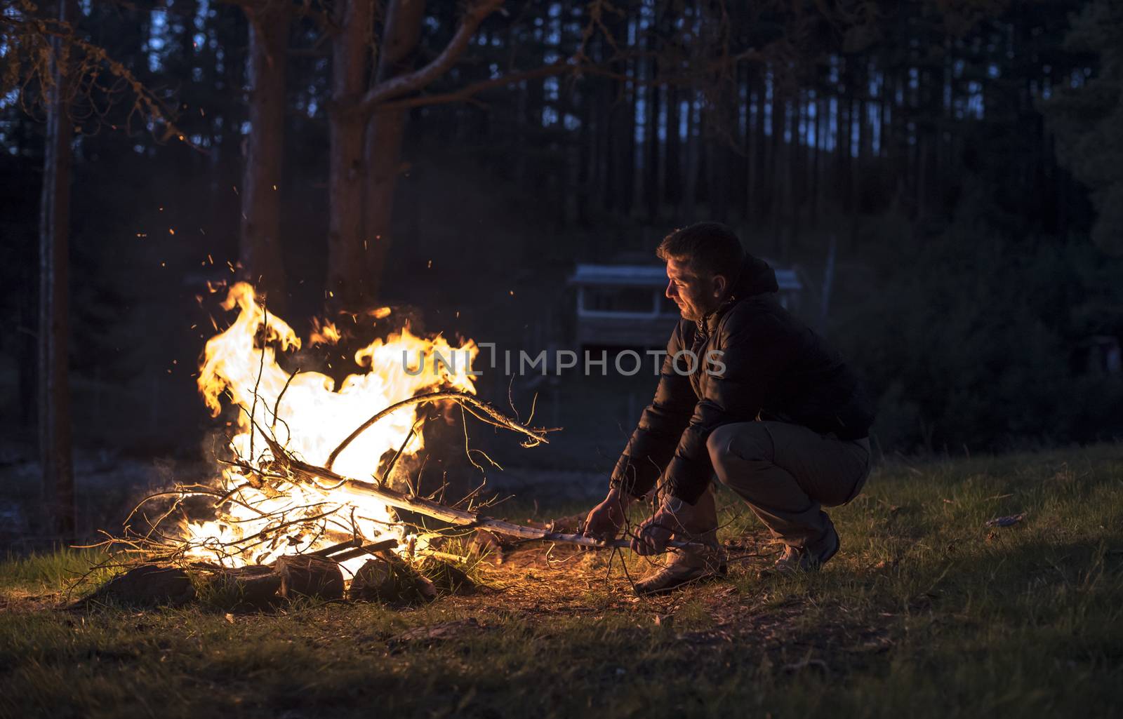 Man lights a fire in the fireplace in nature at night.