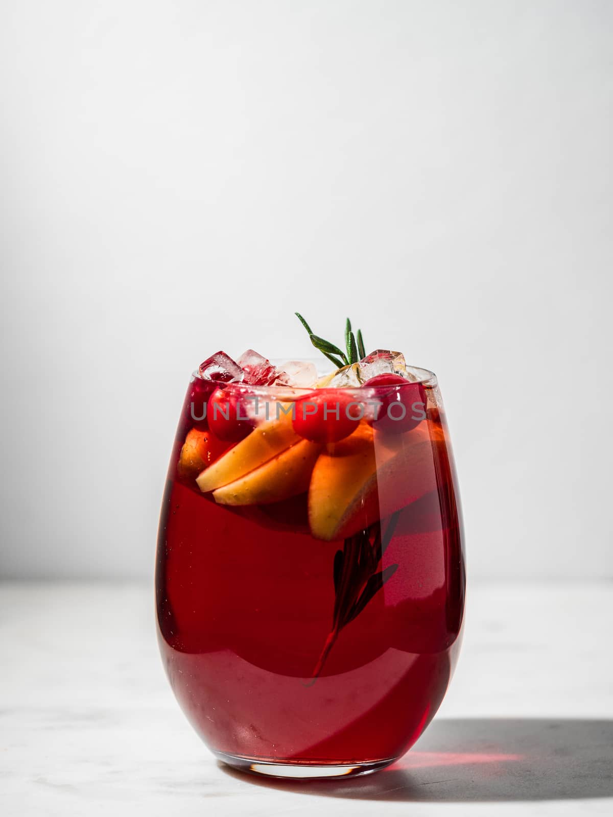 Winter sangria on tabletop. Glasses of sangria with fruit slice, cranberry and rosemary. Vertical. Copy space for text or design.