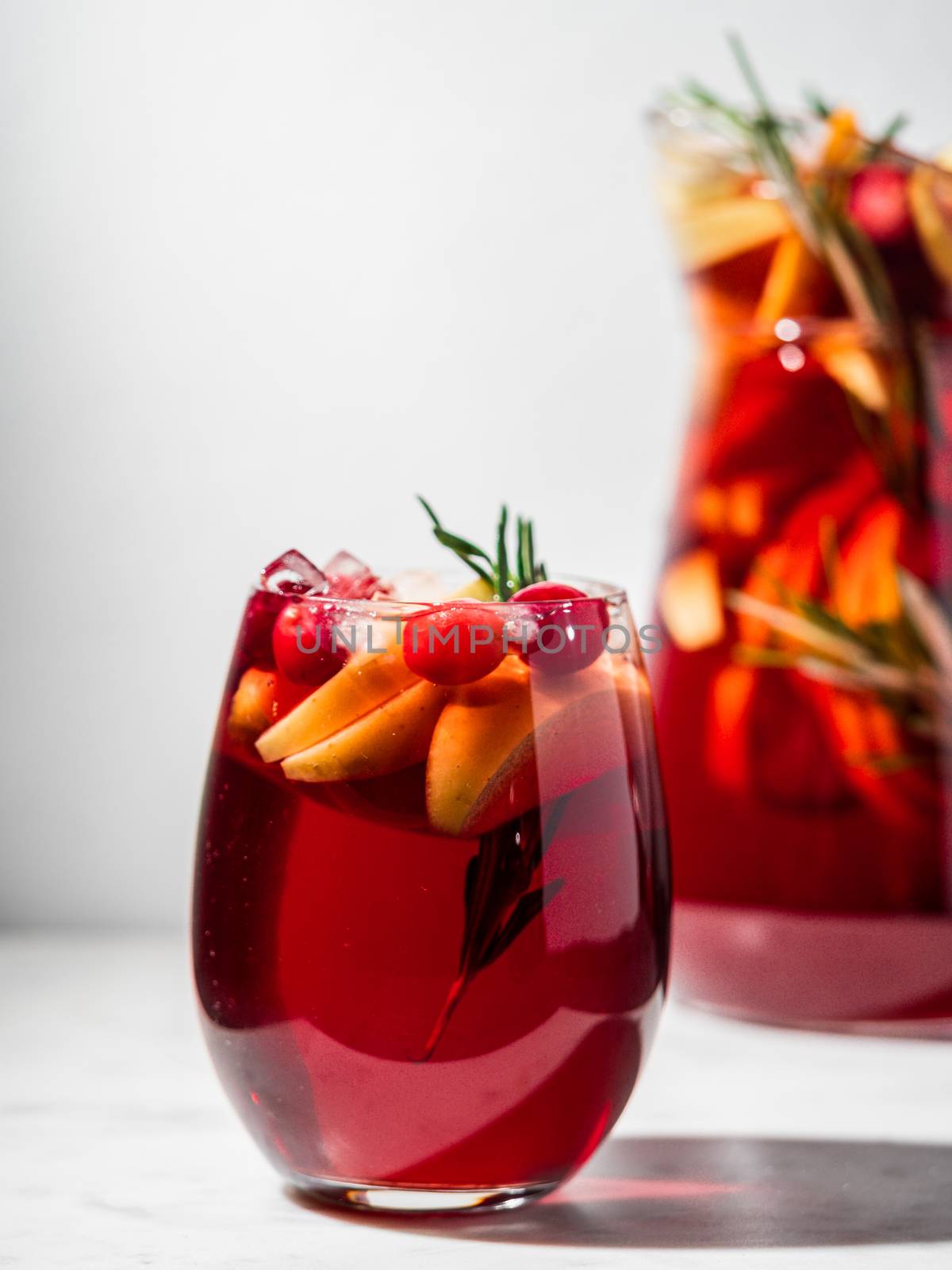 Winter sangria on tabletop. Glasses of sangria with fruit slice, cranberry and rosemary. Vertical. Copy space for text or design.