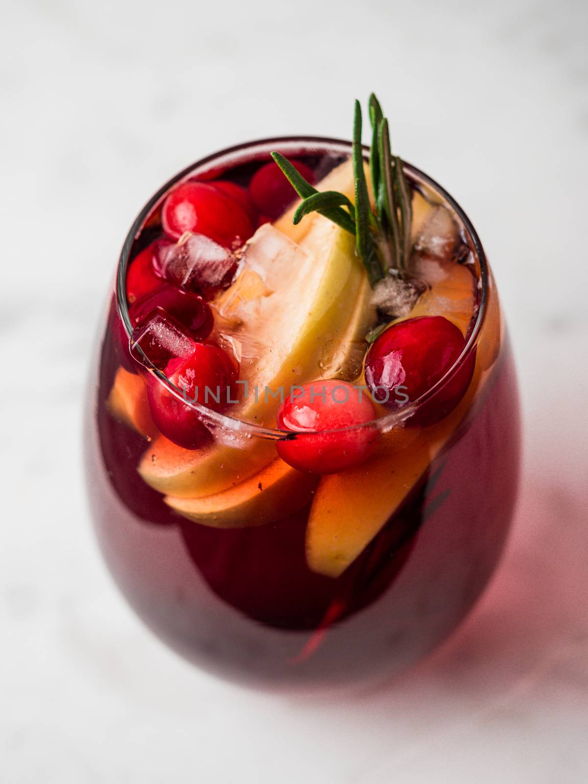 Winter sangria on tabletop with gray linen tablecloth. Glasses of sangria with fruit slice, cranberry and rosemary. Vertical.