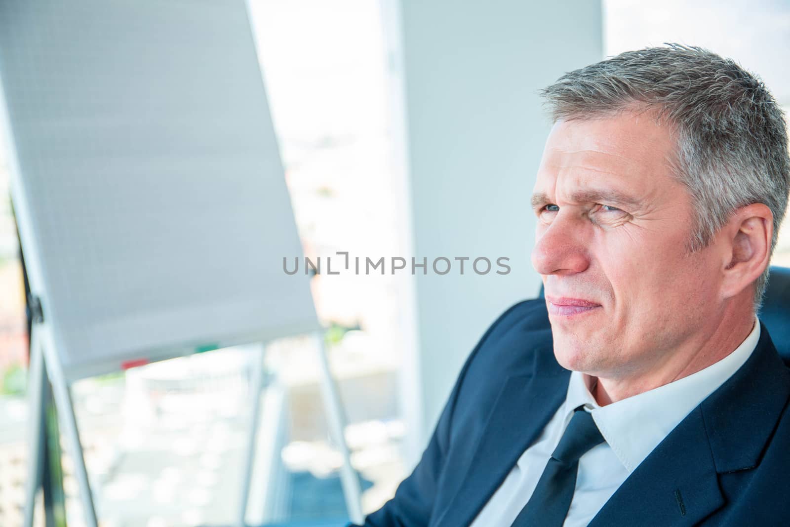 Portrait of mature business man sitting at conference in office with displeased, disappointed, tired facial expression