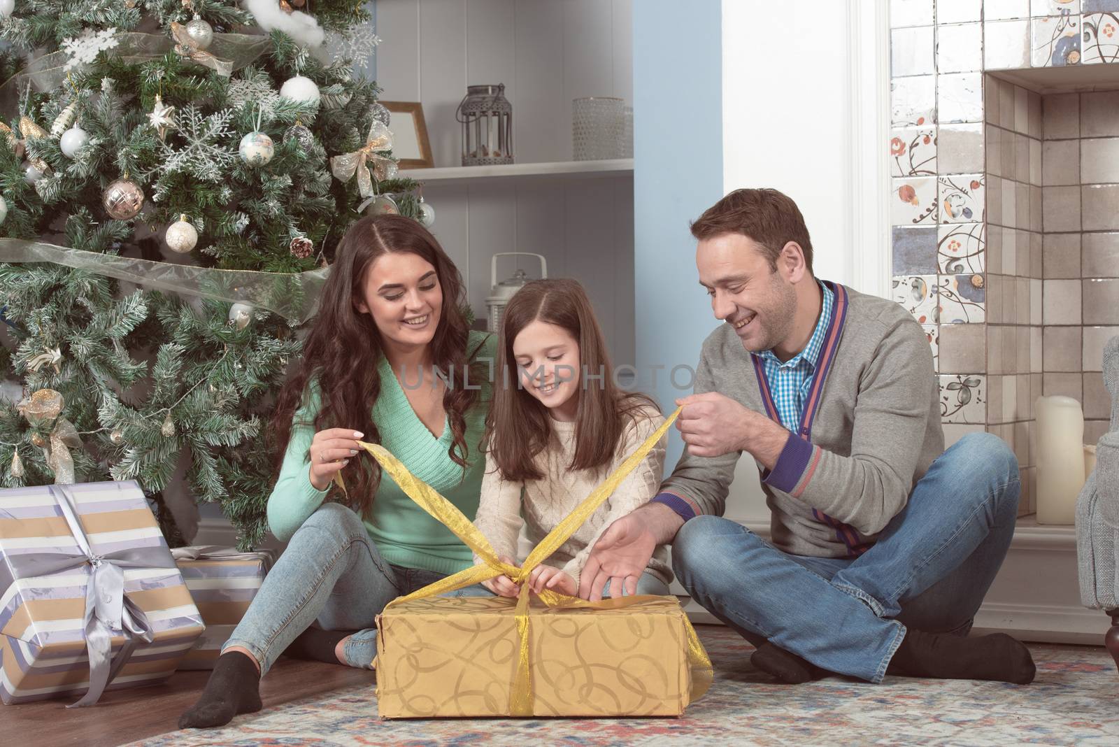 Smiling family unpacking presents with the Christmas tree in the background