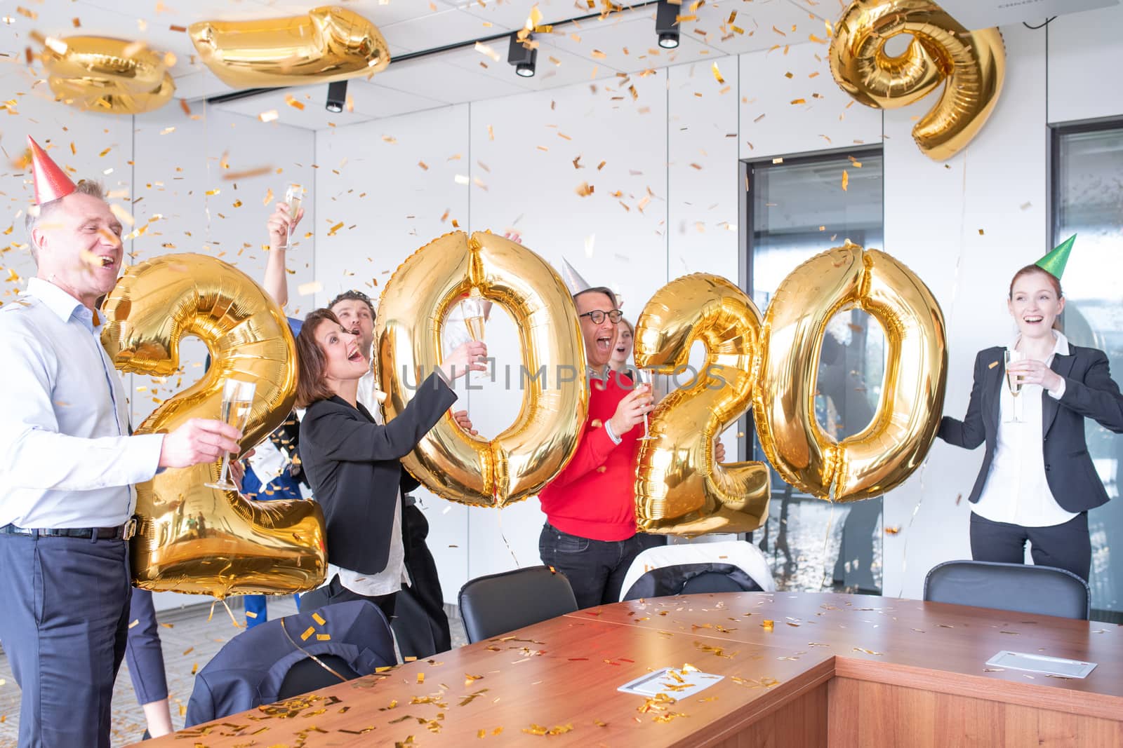 Business people are celebrating holiday in modern office drinking champagne and having fun in coworking. Merry Christmas and Happy New Year 2020 concept