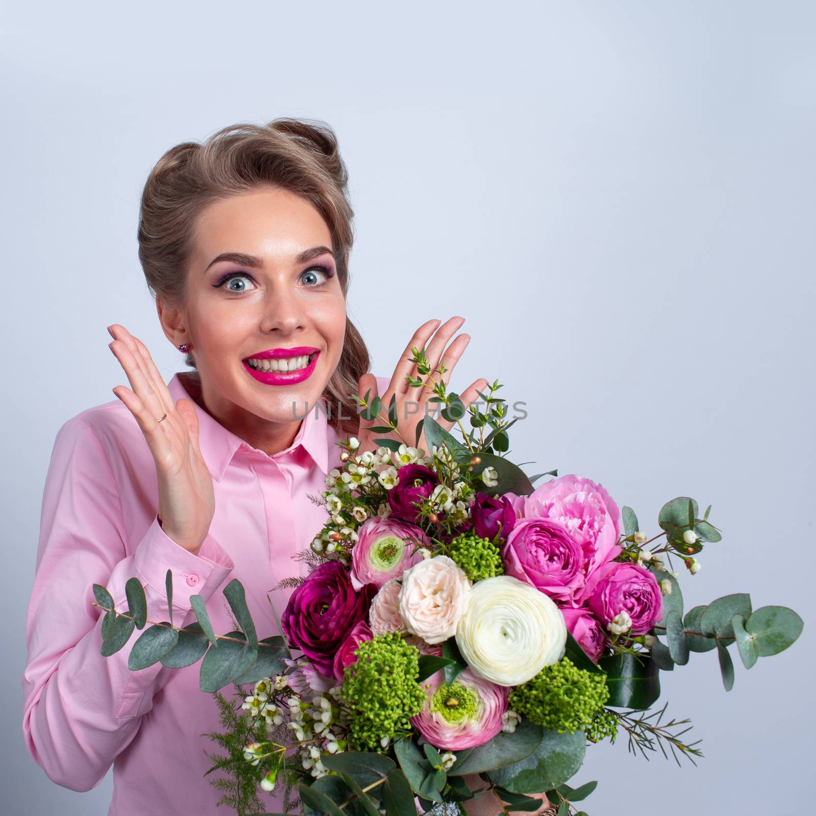 Woman in pink clothes surprised with bunch of flowers for Valentines day, funny emotional expression