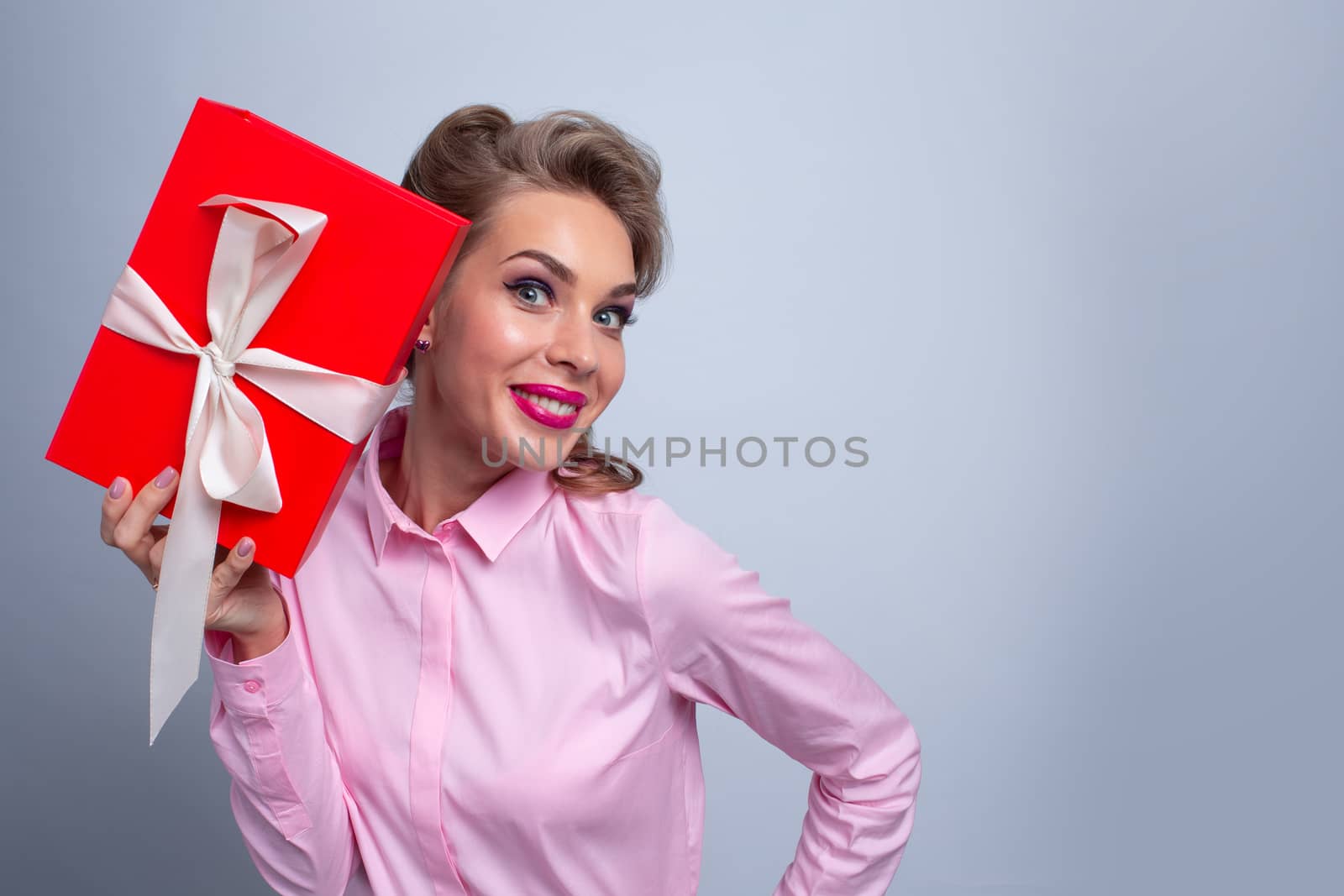 Young woman puts her ear to the present wrapped in red paper Christmas Valentines day concept