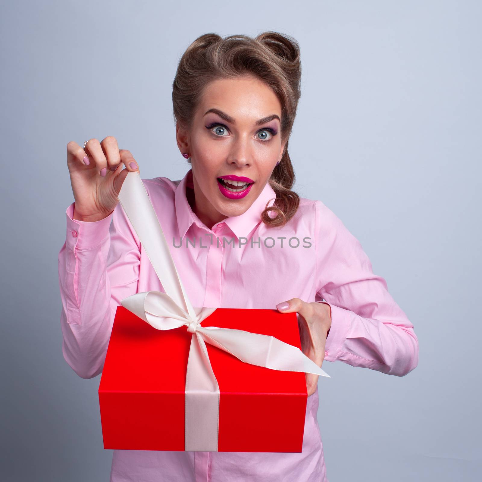 Hmm what is it! Funny woman pulling ribbon of bow on gift box and want to open. Christmas, new year, birthday, Valentine, Valentines day