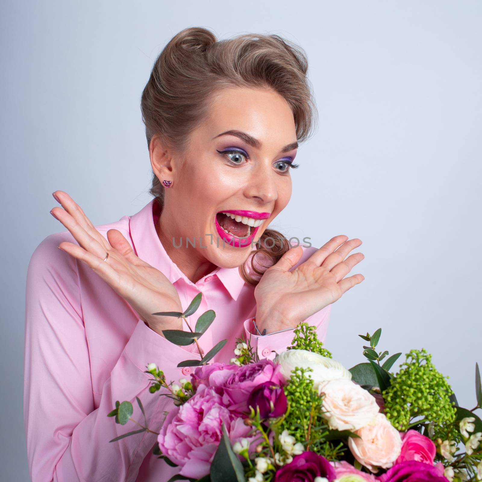 Woman in pink clothes surprised with bunch of flowers for Valentines day, funny emotional expression