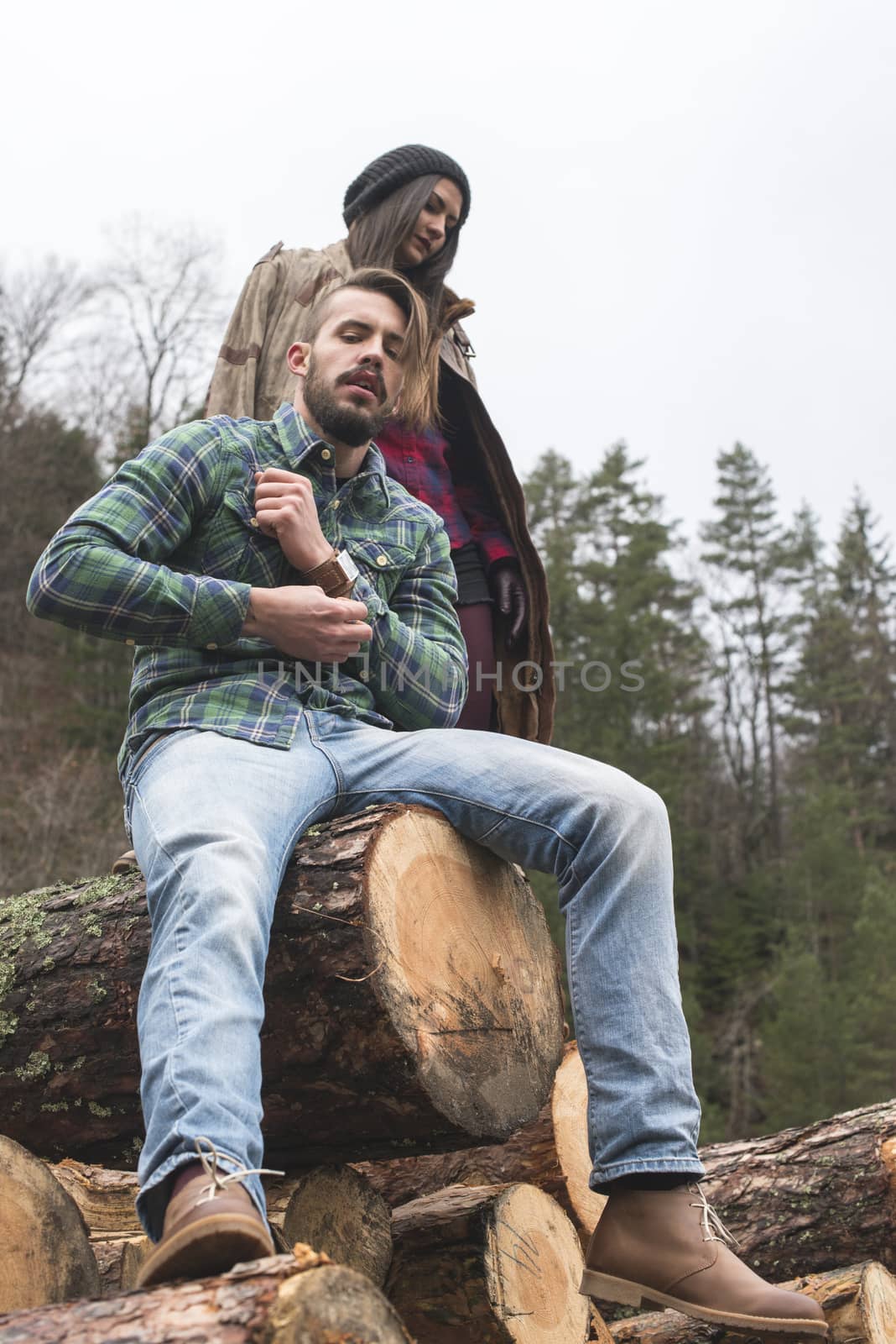 Young woman and men on wood logs in the forest