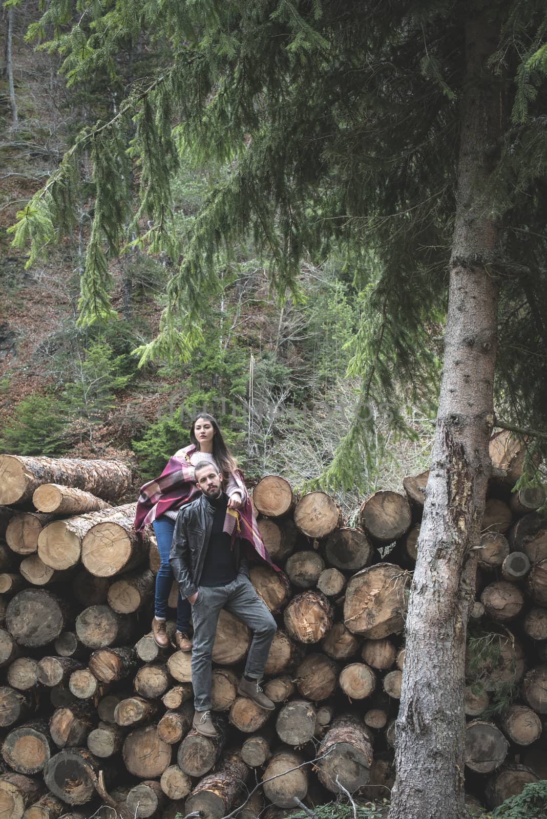 Young woman and men on wood logs in the forest