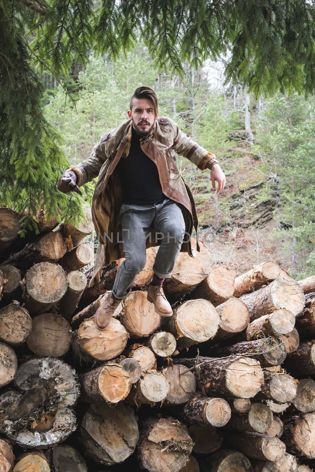 Young men jumping on logs in the forest.  by deyan_georgiev