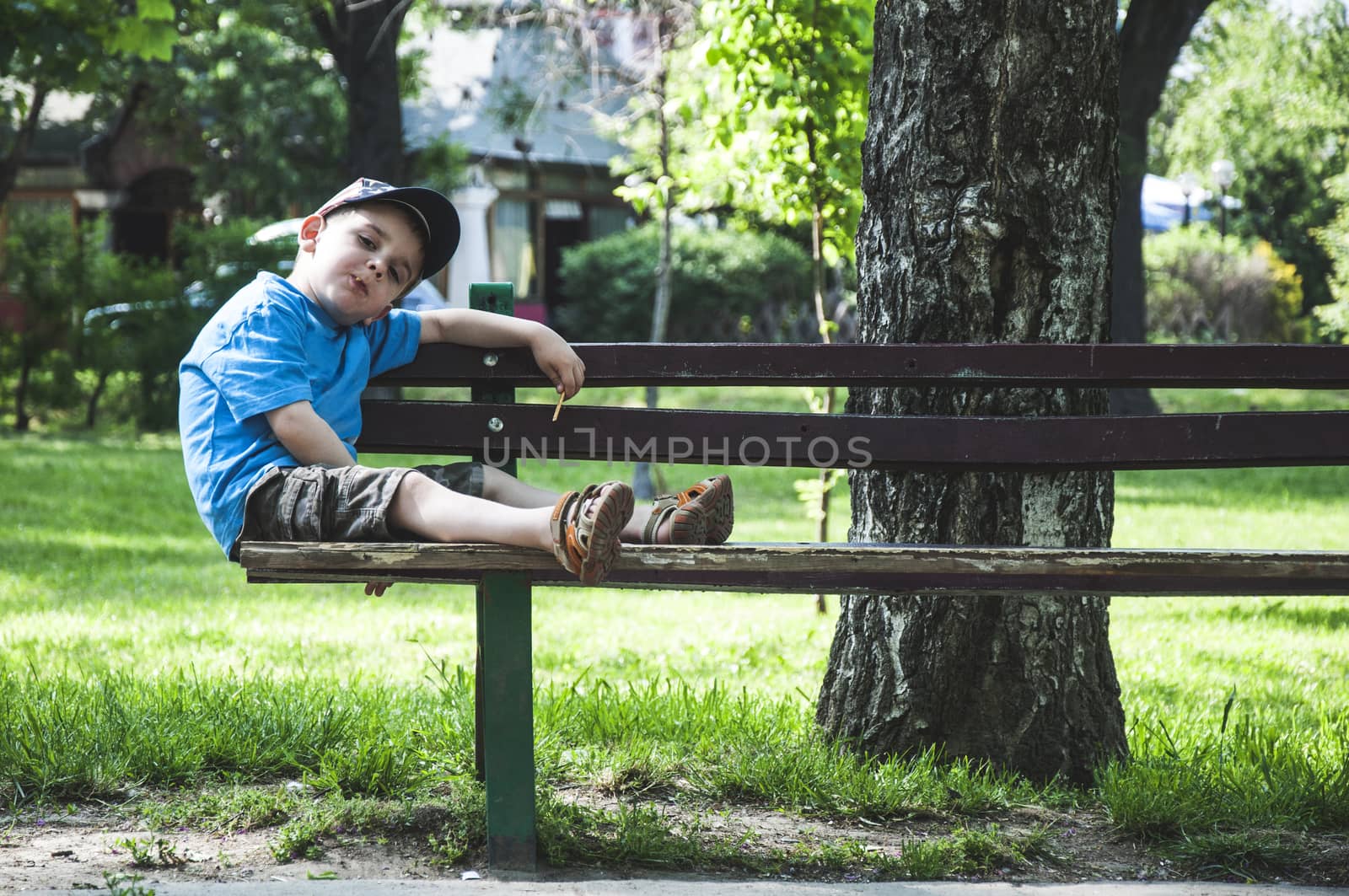 Little boy on a bench in the park. 