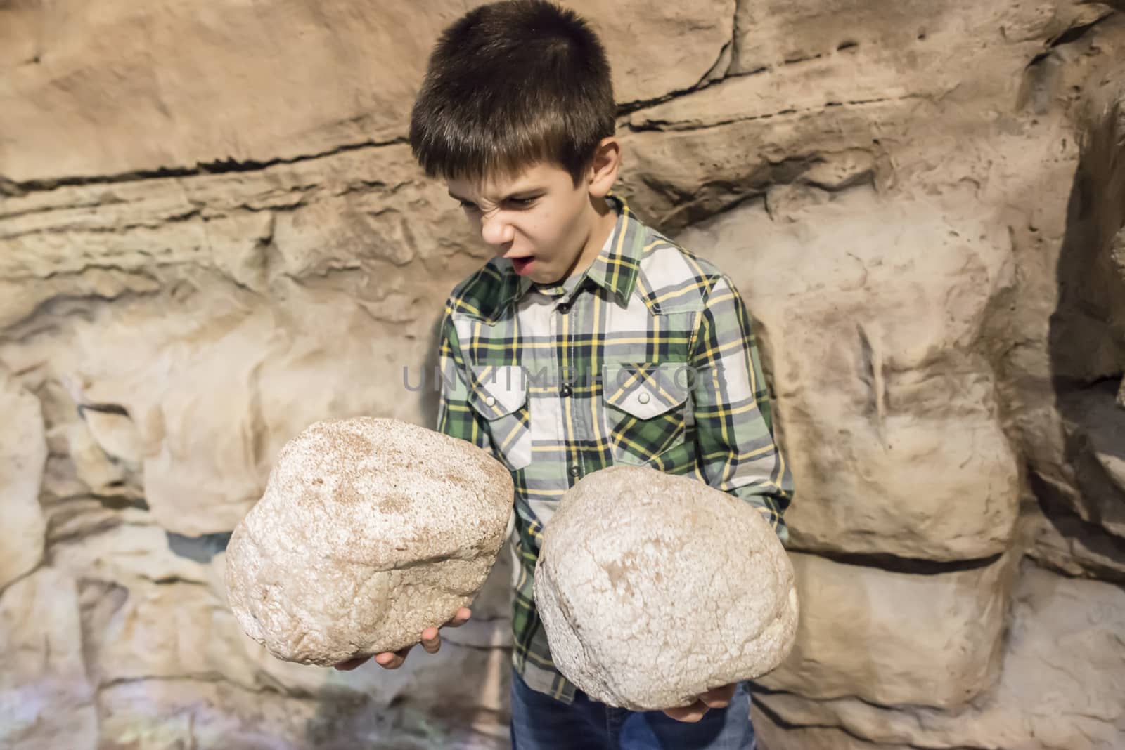 Strong child holds heavy stones. 