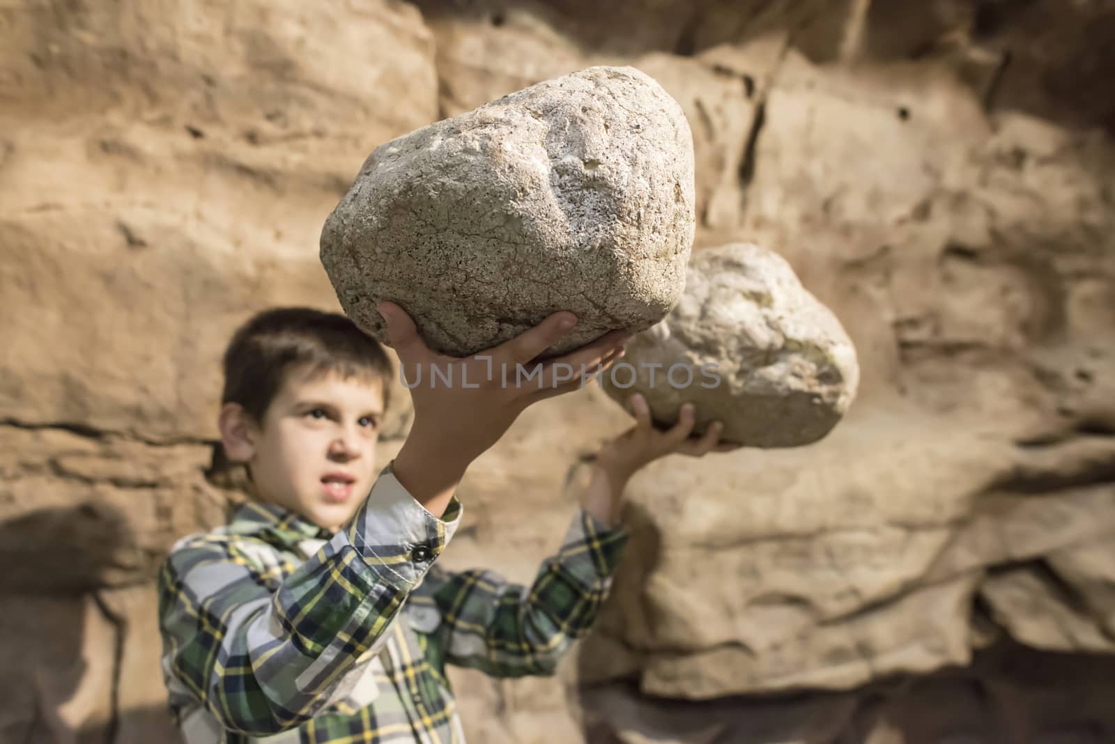 Strong child holds heavy stone by deyan_georgiev