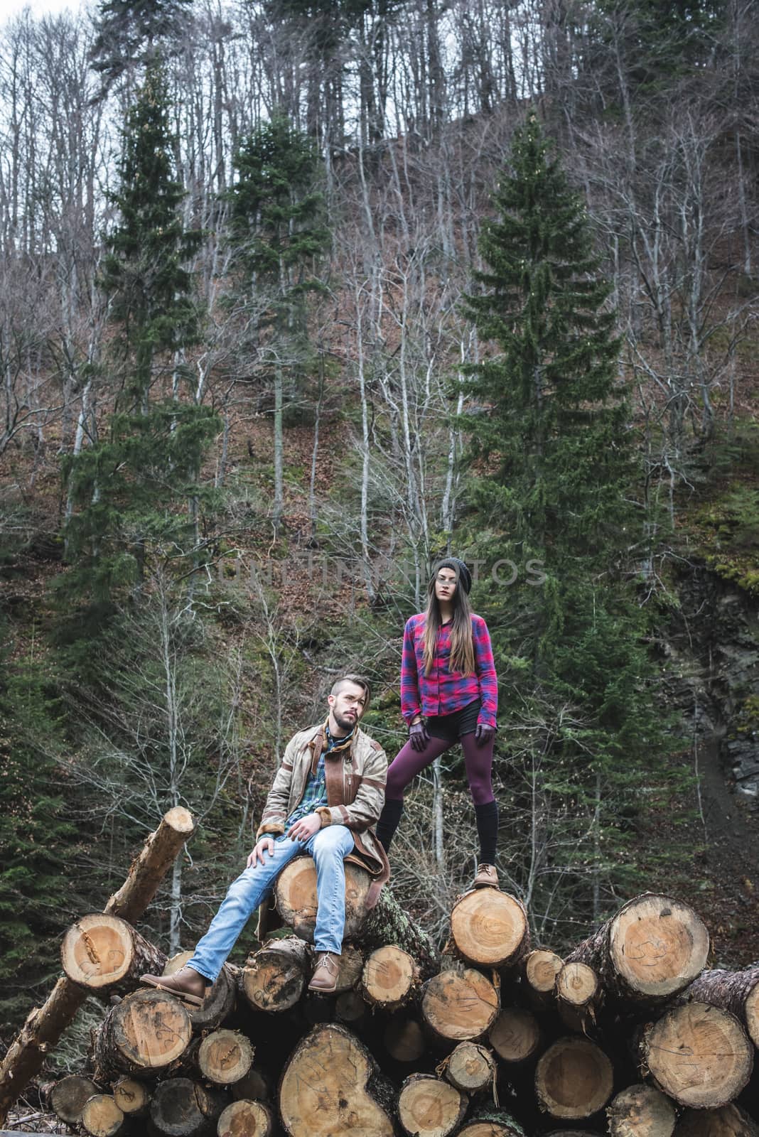 Young woman and men on wood logs by deyan_georgiev