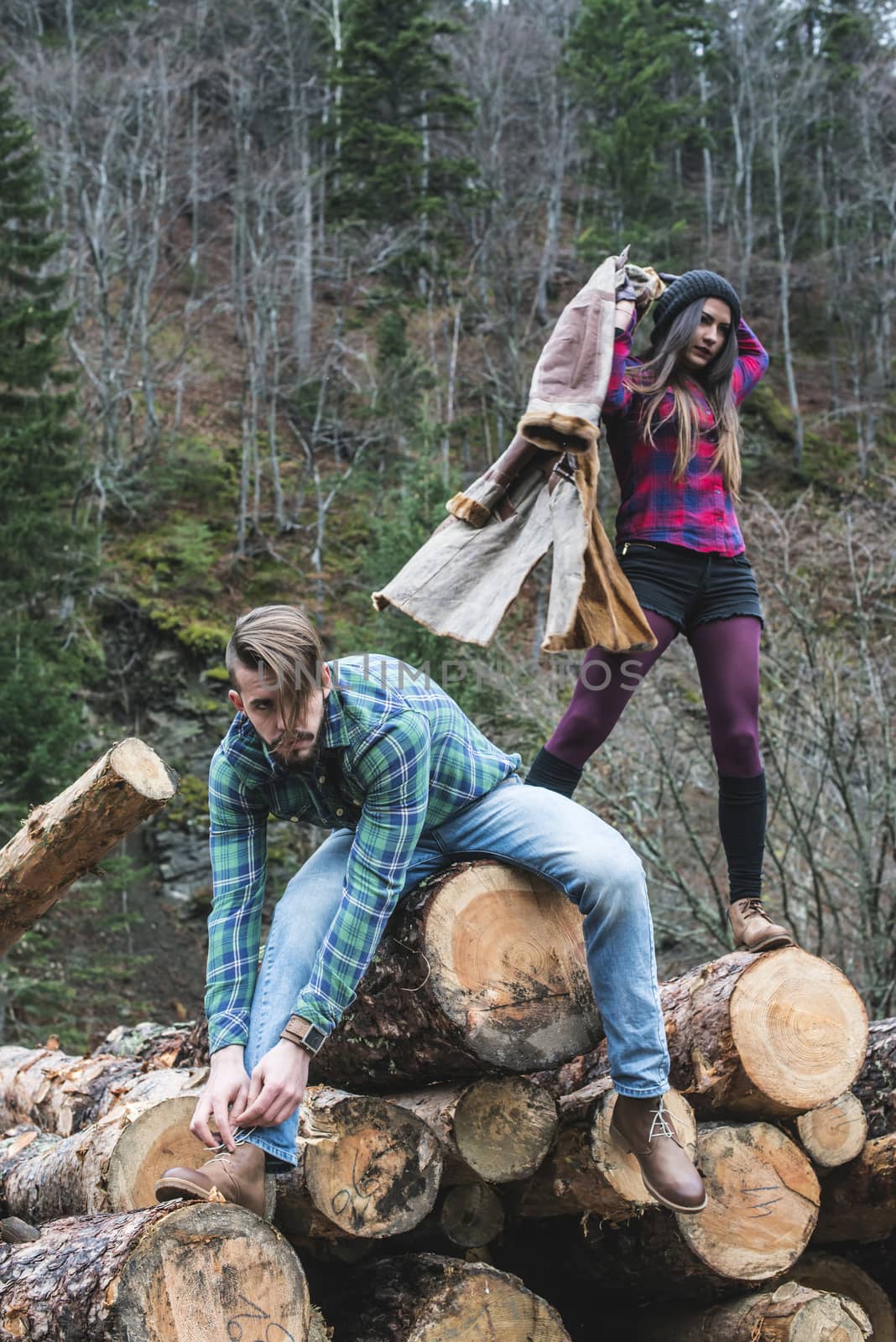 Young woman and men on wood logs in the forest