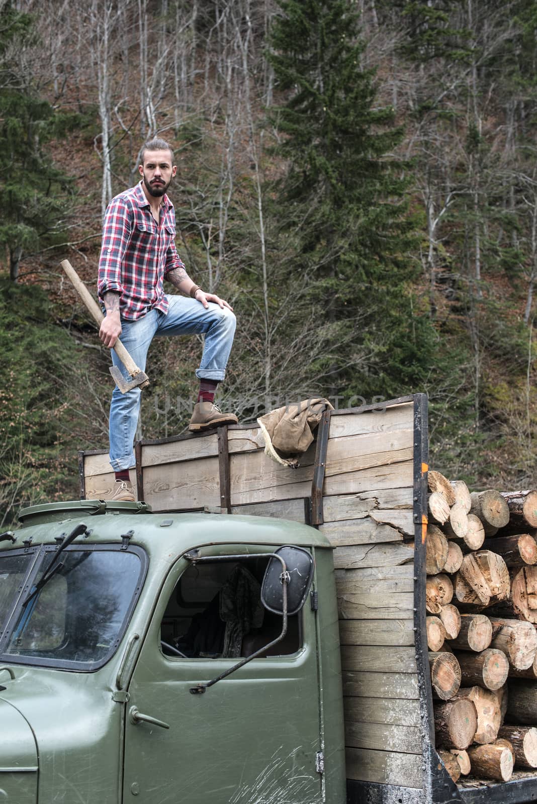 Young man on vintage truck with logs by deyan_georgiev