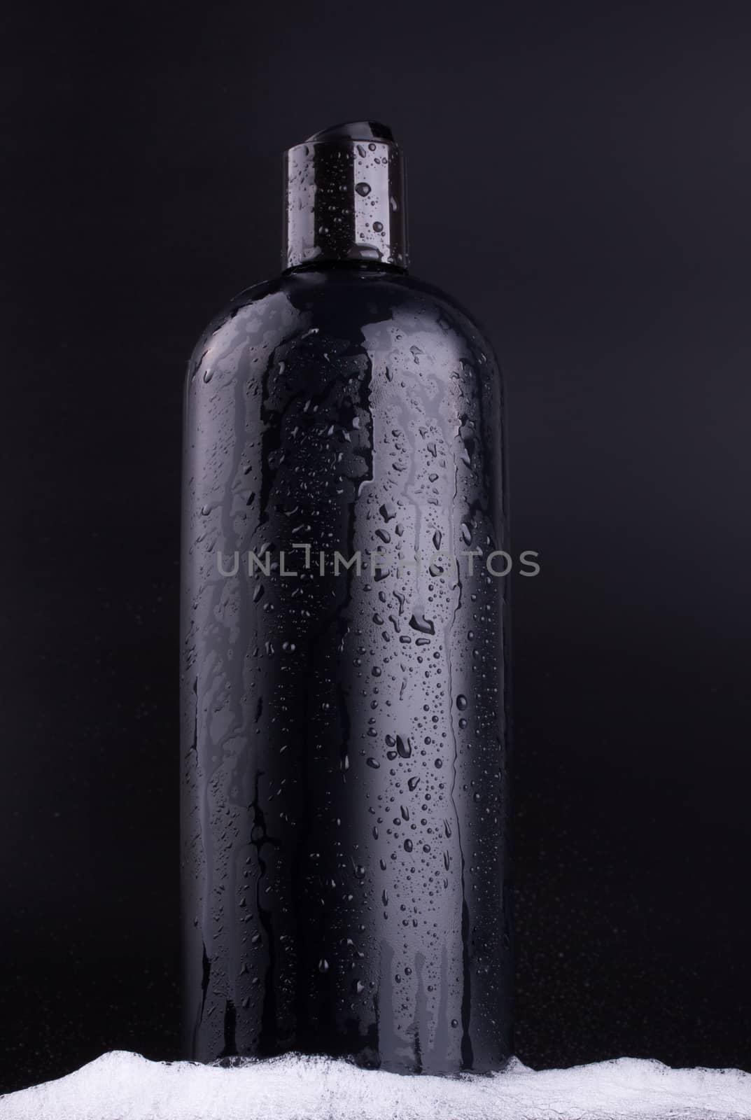 Black shampoo bottle on black background by lanalanglois