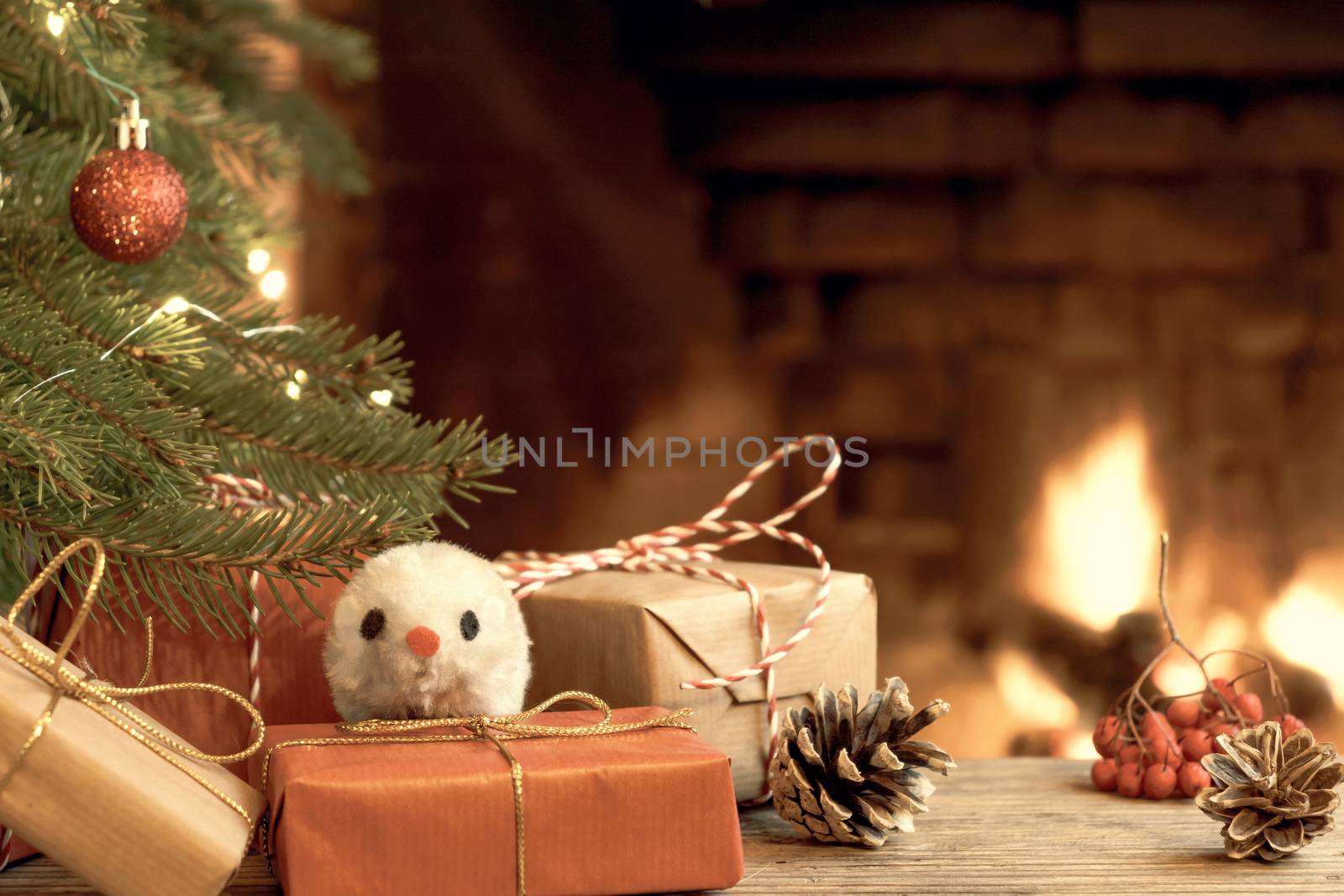 Christmas composition - mouse is symbol of 2020 according to Chinese horoscope next to gifts under Christmas tree in room by fireplace by galsand