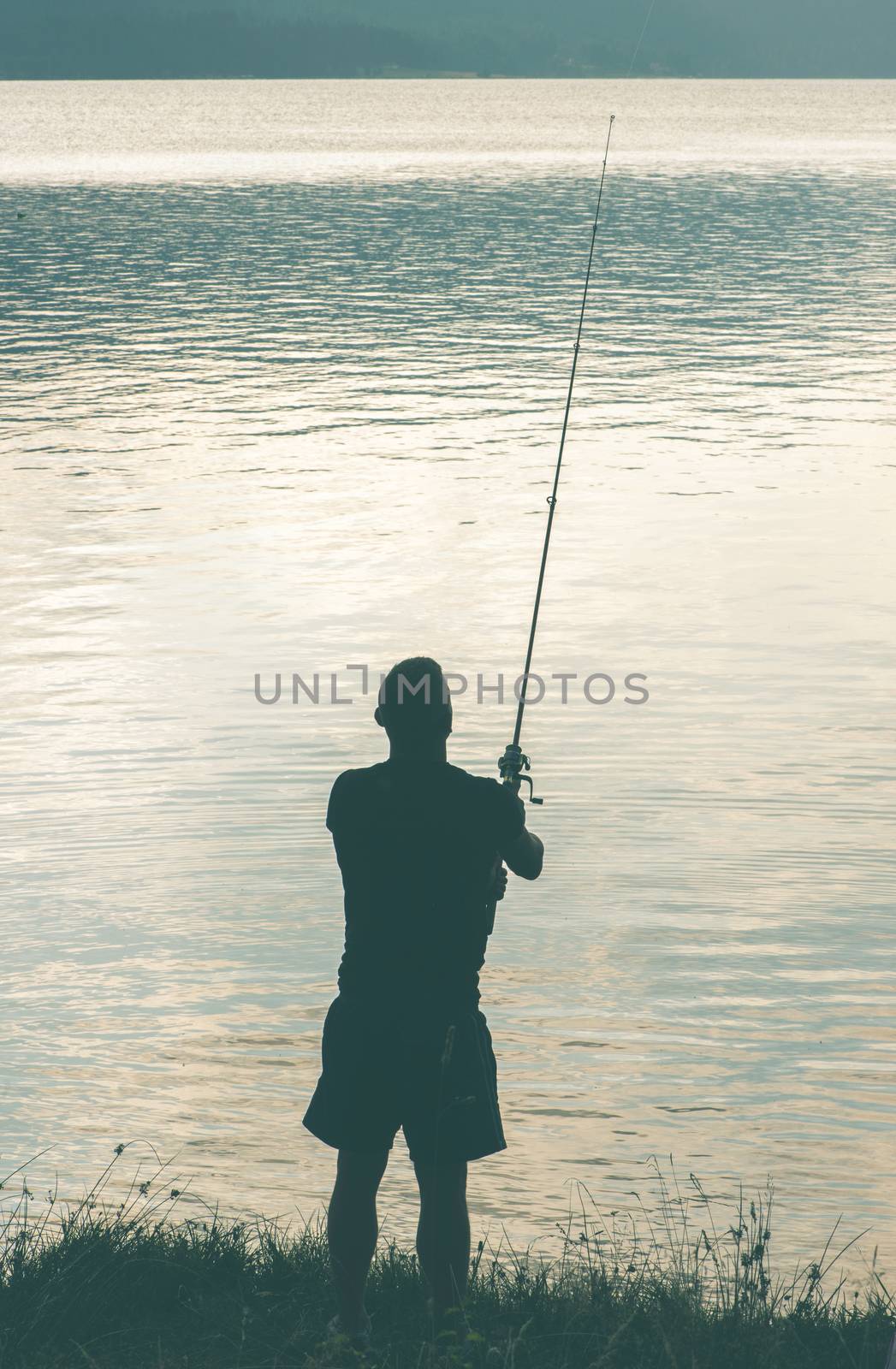 Silhouette of fisherman. Mountain dam