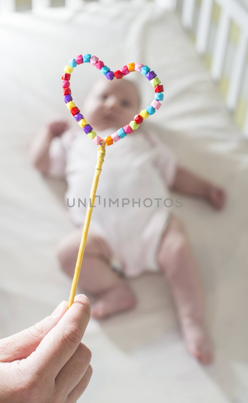 Baby in a bed in frame of heart shape. Out of focus baby