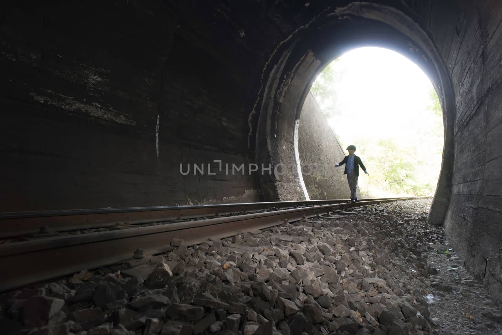 Child walking in railway tunnel. Vintage clothes