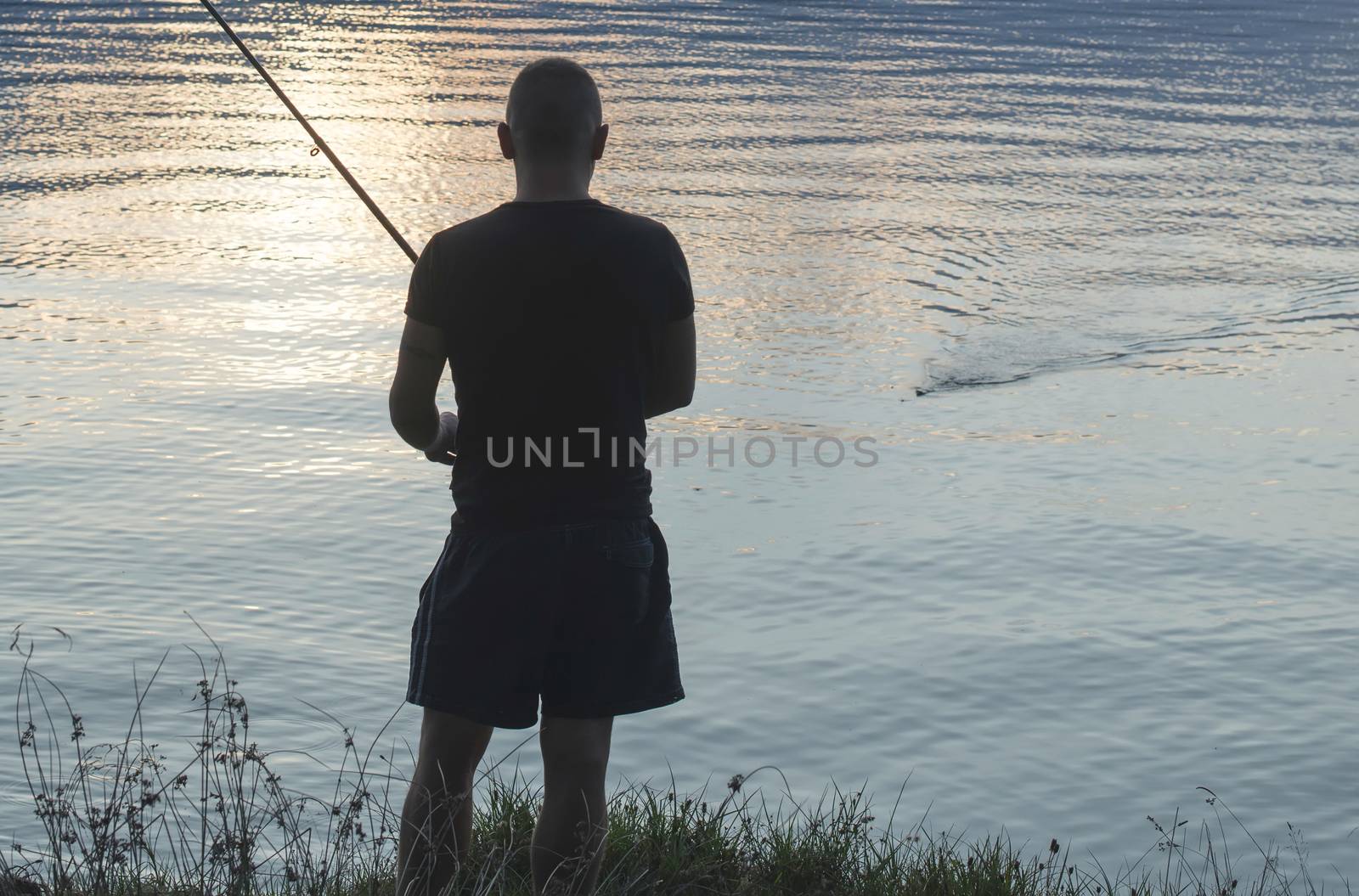 Silhouette of fisherman. Mountain dam