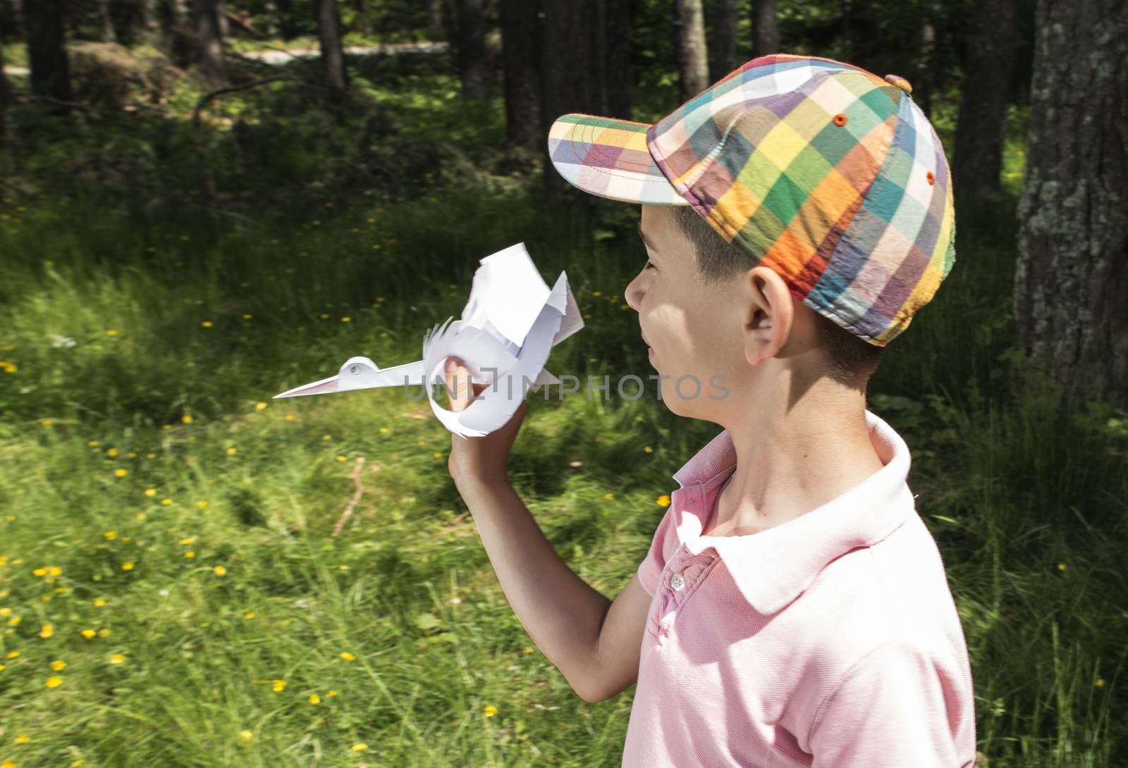 Child play with a stork made of paper. Forest