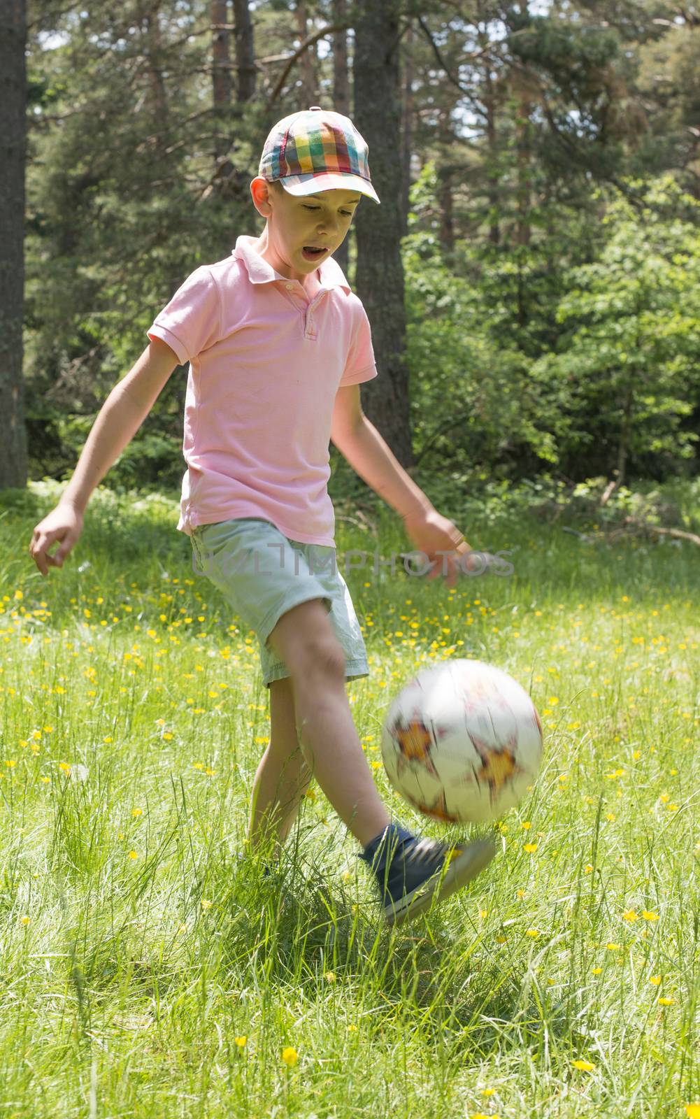Child play with a ball in the mountain. Green grass