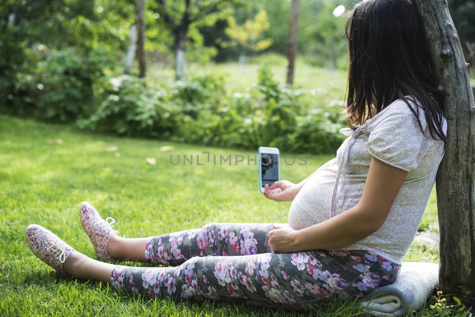 Pregnant women with smartphone in a garden