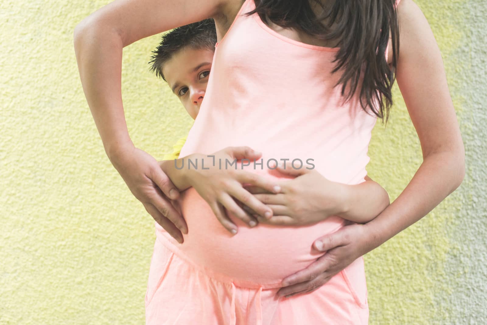 Pregnant women and small boy. Yellow wall