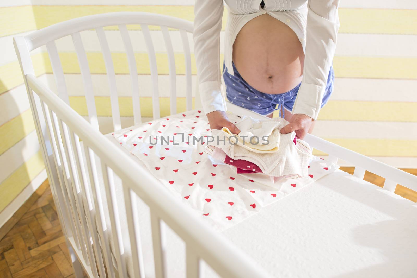 Pregnant women in a baby room. Preparing the room for the baby