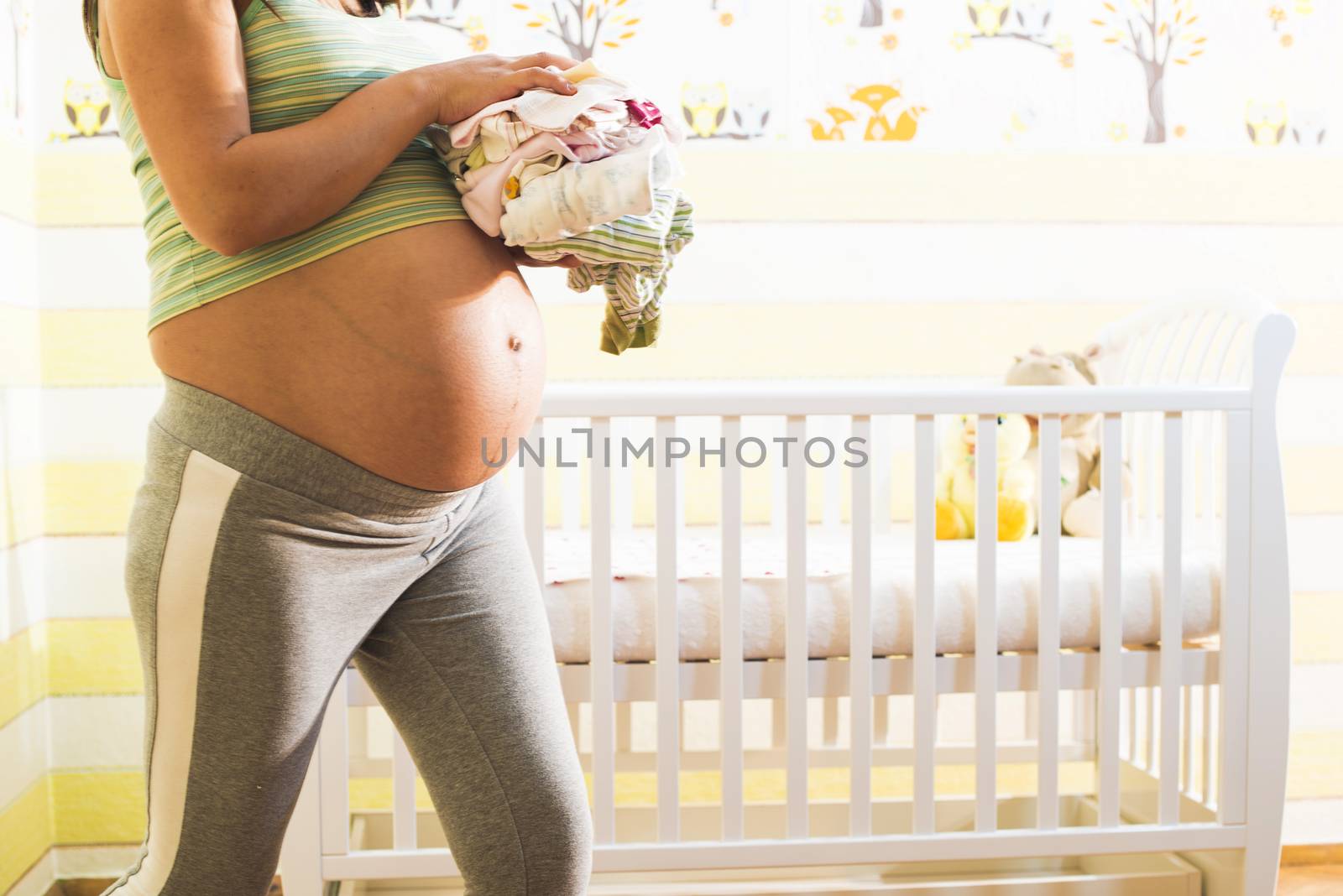 Pregnant women in a baby room. Preparing the room for the baby